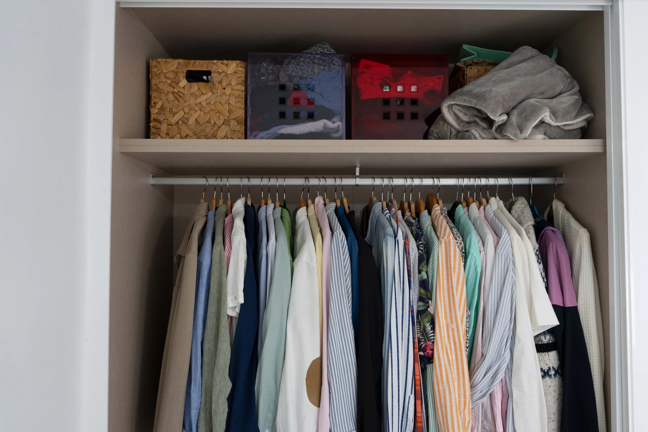 Armario con ropa colgada y cajas de almacenamiento en la parte superior