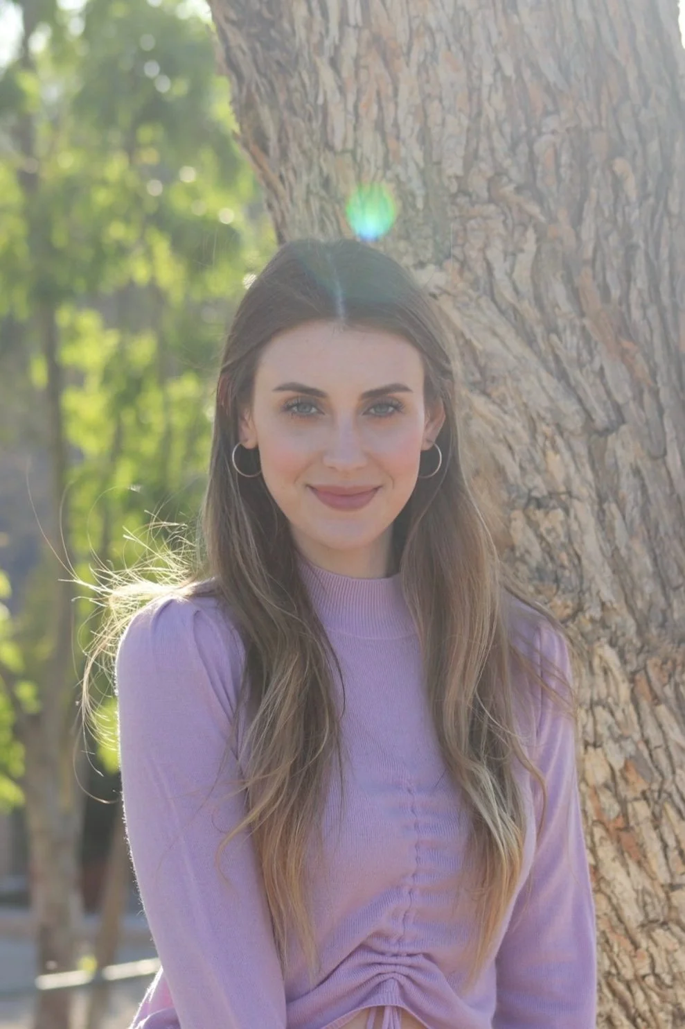 An eating disorder therapist serving Los Angeles posing in front of tree looking compassionately at the camera.