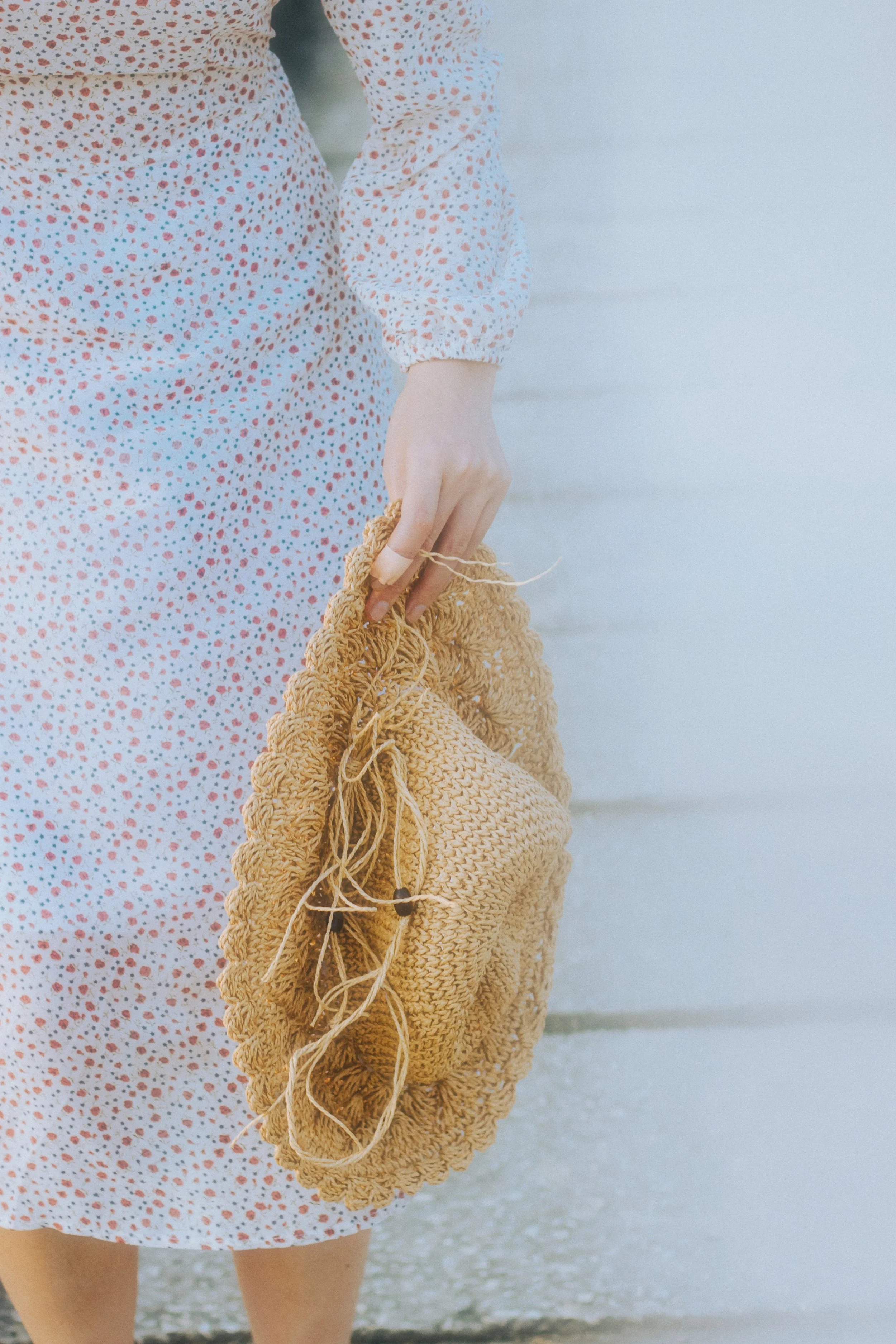 Millennial woman holding a hat by her side in a relaxed posture.