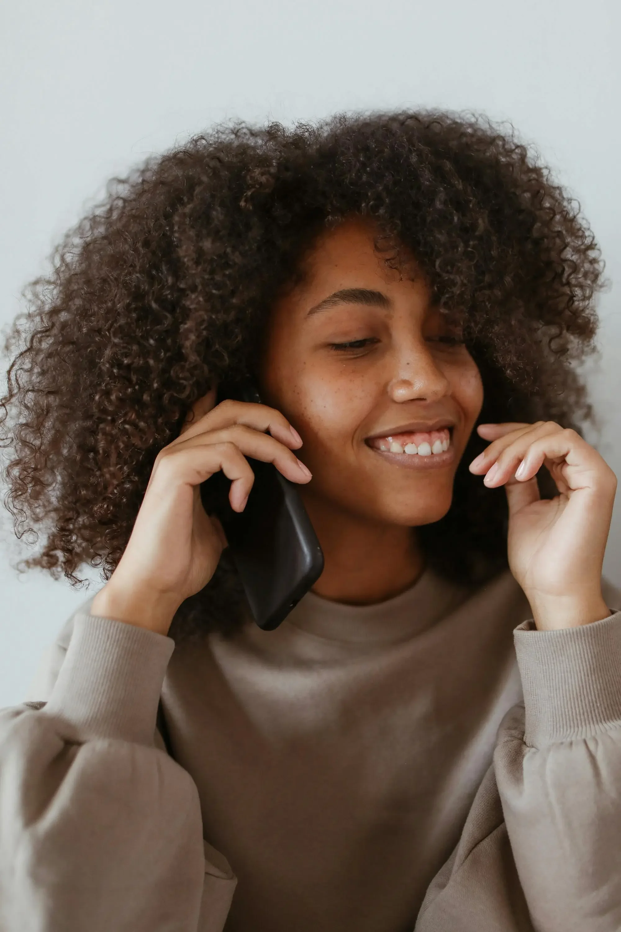Young woman looking hopeful on the phone representing calling a therapist