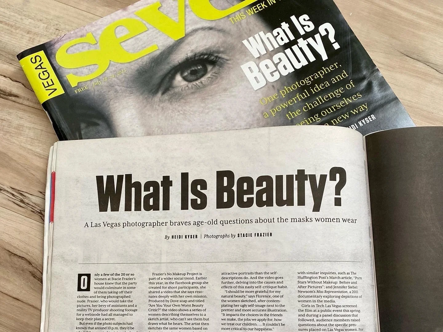 Open magazine on a wooden surface showcasing an article titled 'What Is Beauty?' with a black-and-white photograph of a woman's eye on the cover and a similar headline inside.