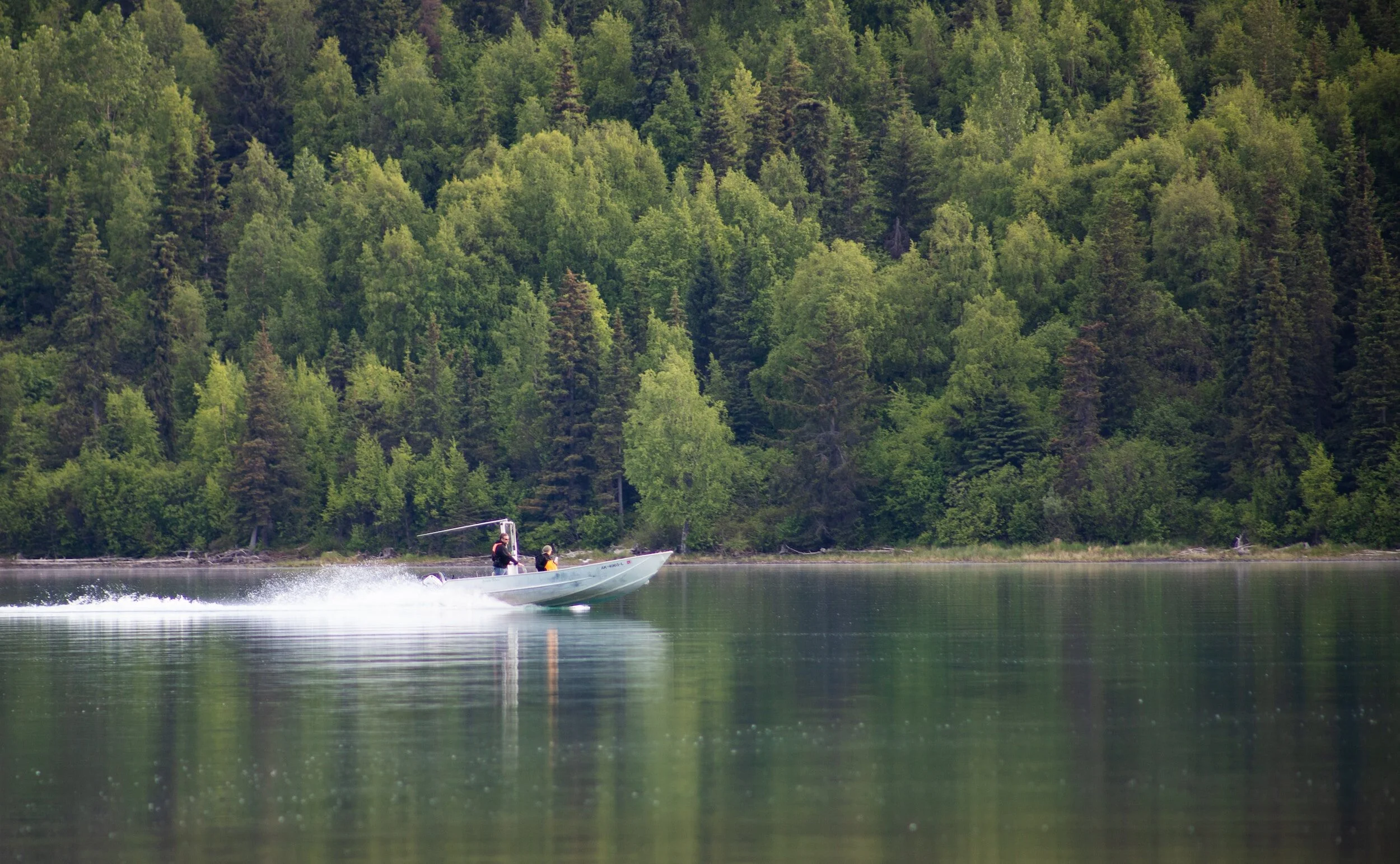Couple out on the water in Ontario with their speedboat and forest trees in the background