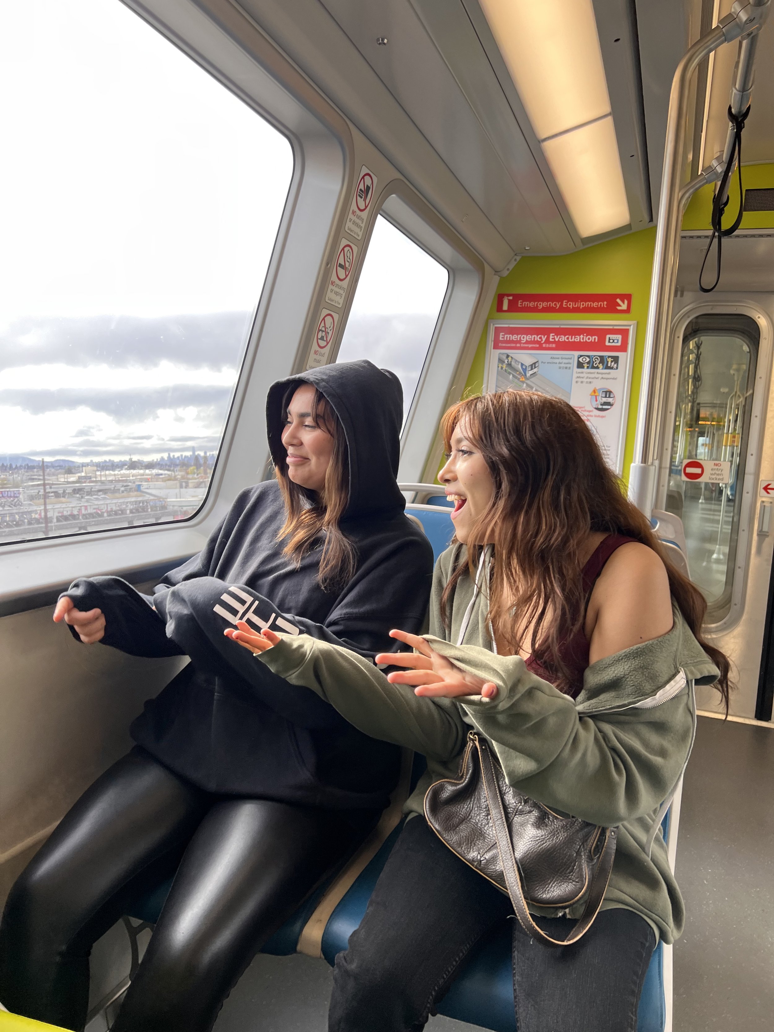  Two youths are laughing, seated on a BART Train 