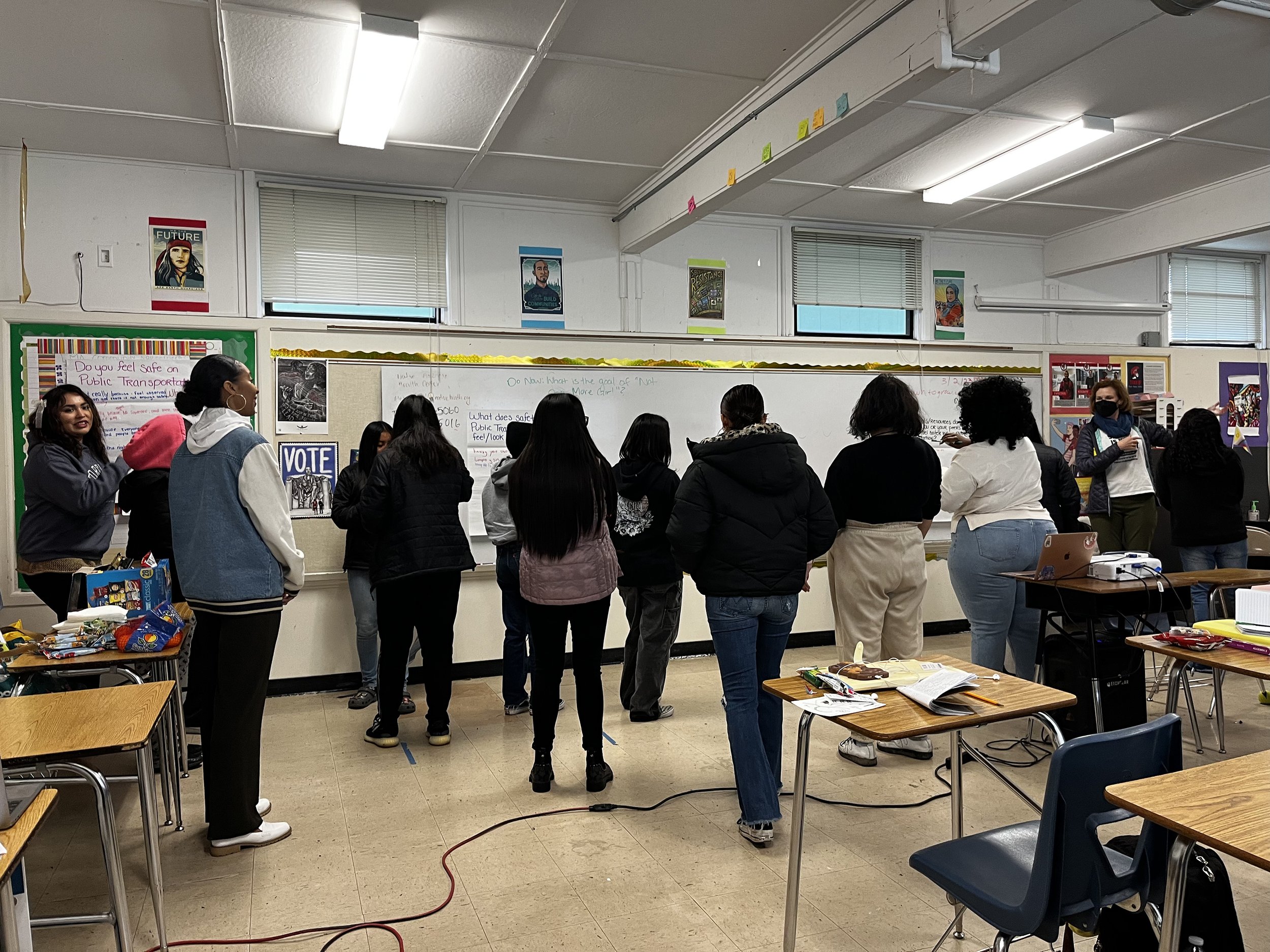  Back of a group of young students facing a white board in a classroom 