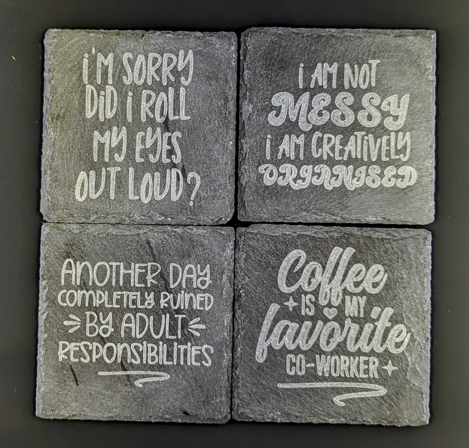 Four square coasters with humorous quotes: "I'm sorry did I roll my eyes out loud?", "I am not messy I am creatively organized", "Another day completely ruined by adult responsibilities", "Coffee is my favorite co-worker".