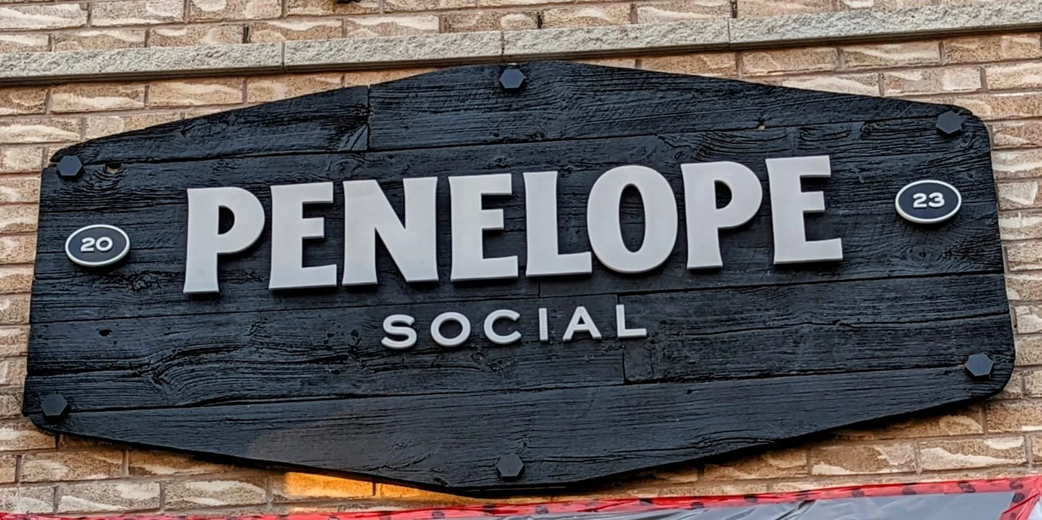 Sign saying 'Penelope Social' with '2023' on a wooden background.