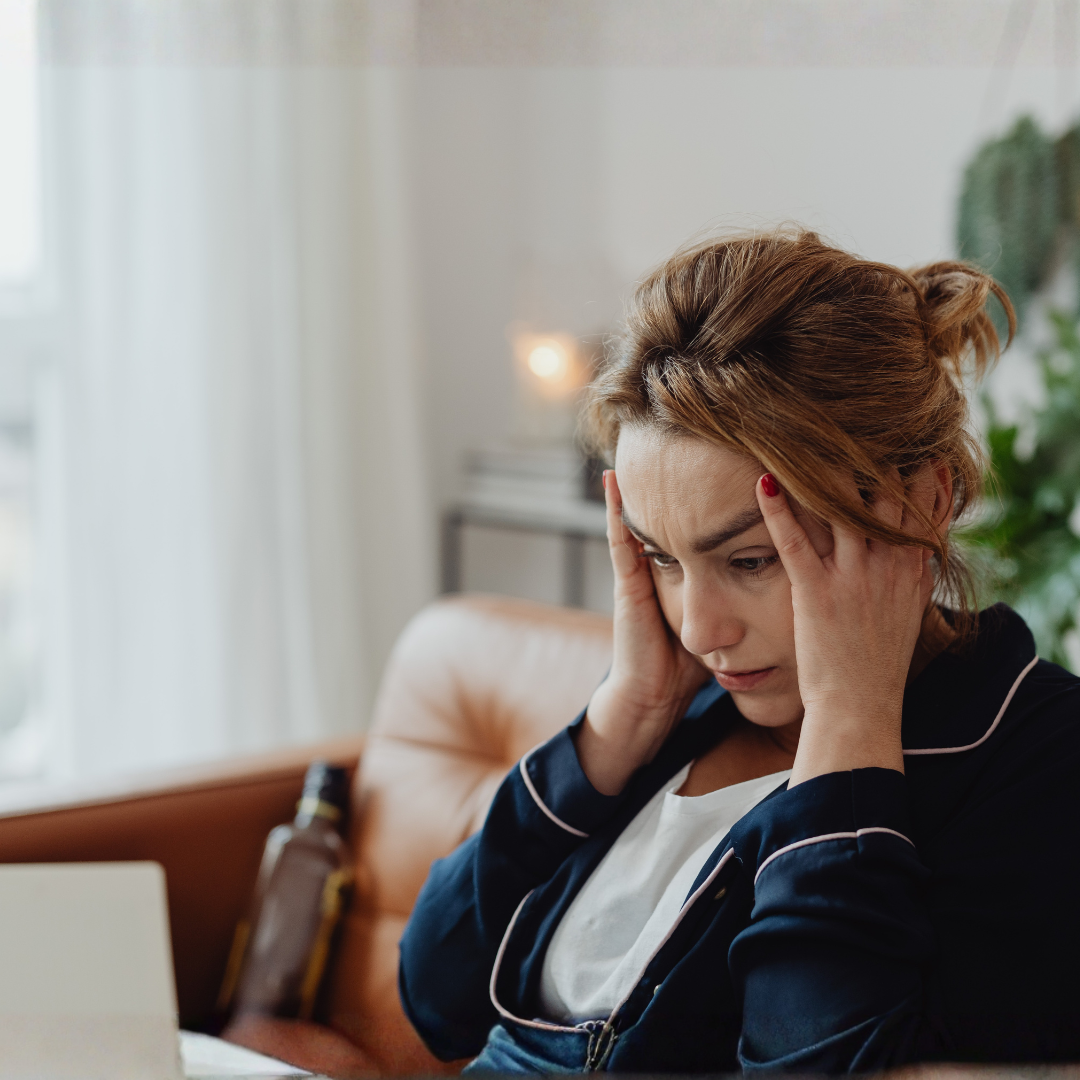 Woman seated and rubbing her temples with a stressed face