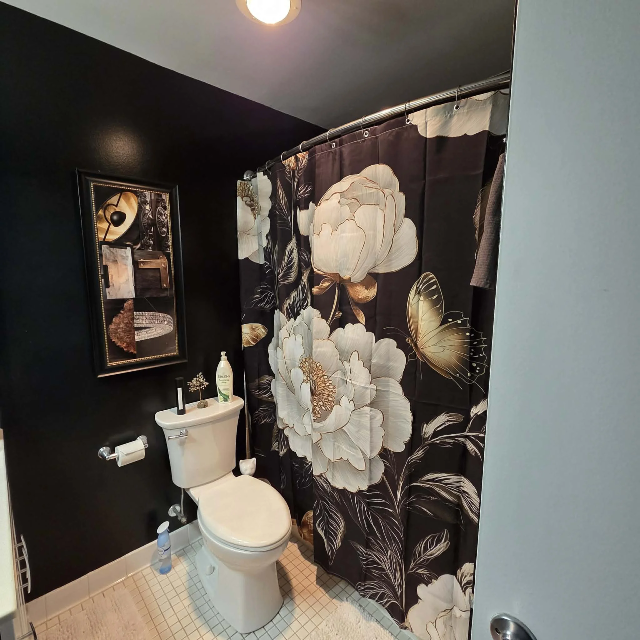 Image of a beautiful designed bathroom with a purple shower curtain with flowers and butterflies on it.