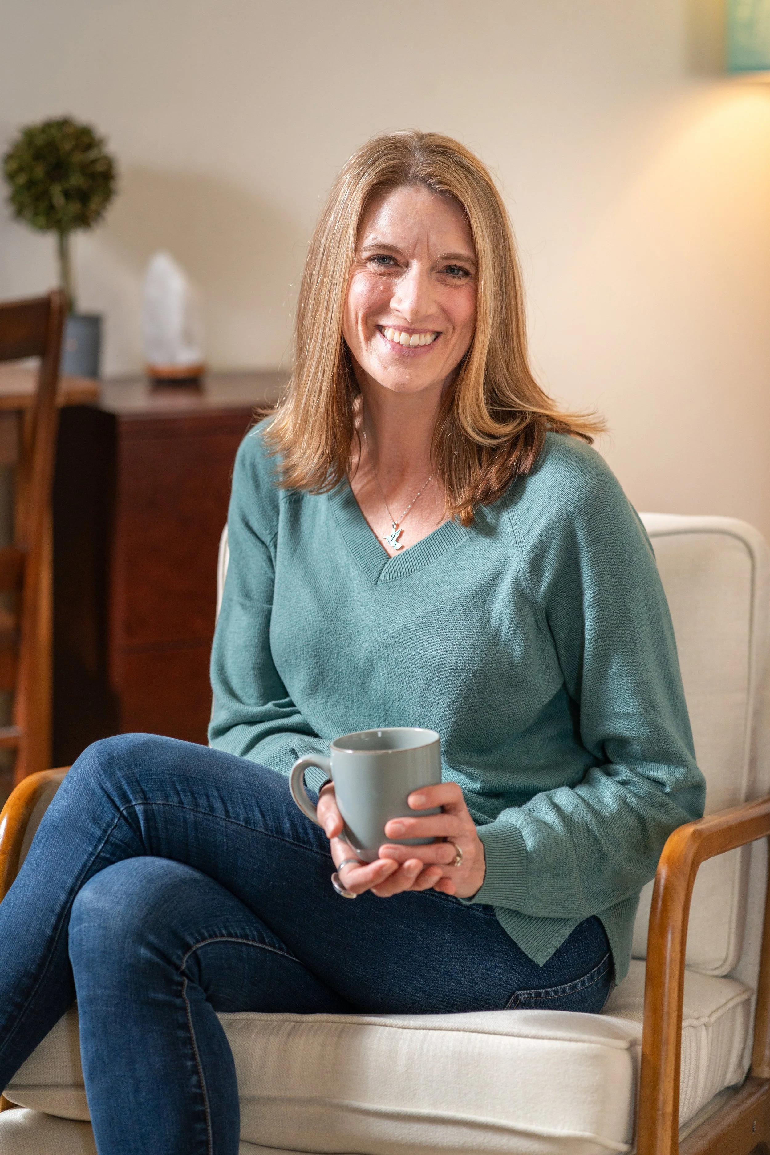 Reagan Glover, LMFT, a licensed marriage and family therapist in California, smiling while seated in her therapy office