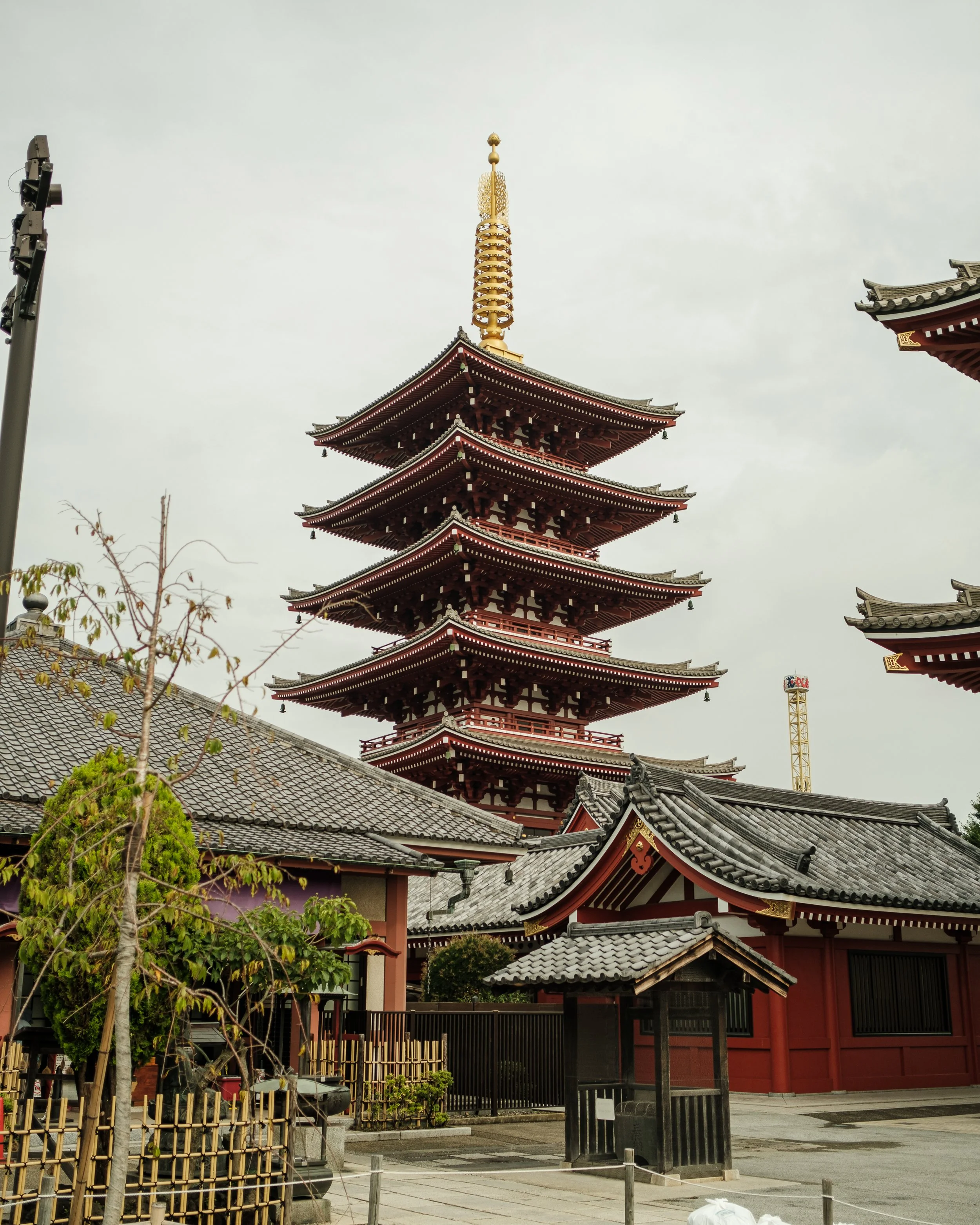 Five-story Japanese pagoda with ornate roofs and a spire, surrounded by traditional buildings and trees.