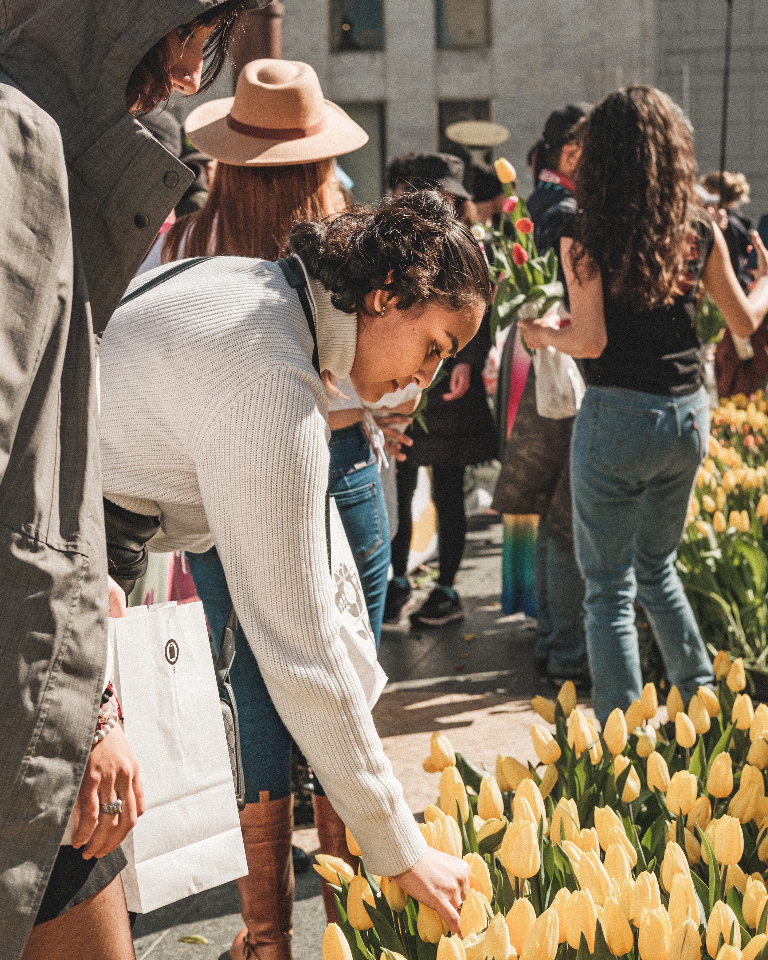 People shopping at an outdoor flower market with yellow tulips.