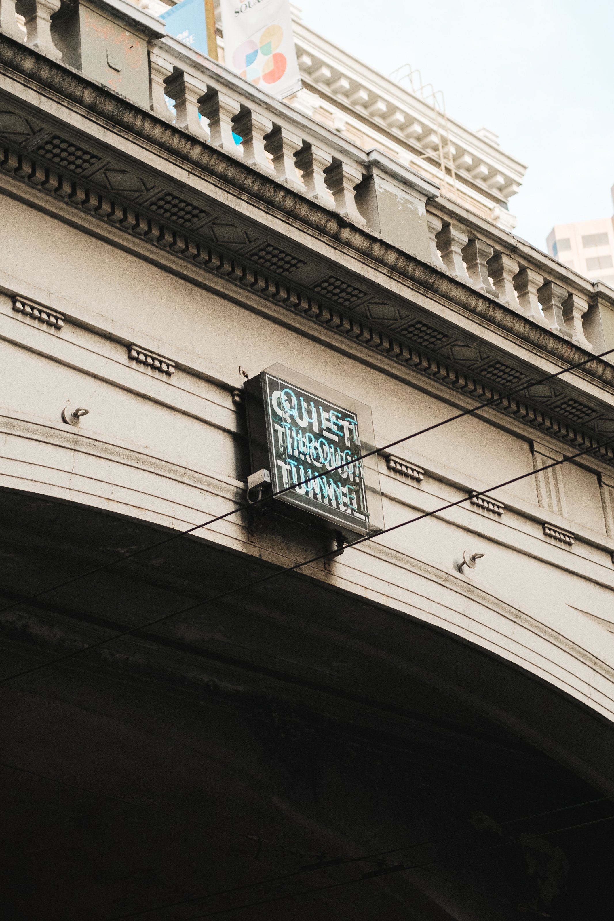 Neon sign on a building spine that reads "Quiet Through Tunnel" in capital letters.