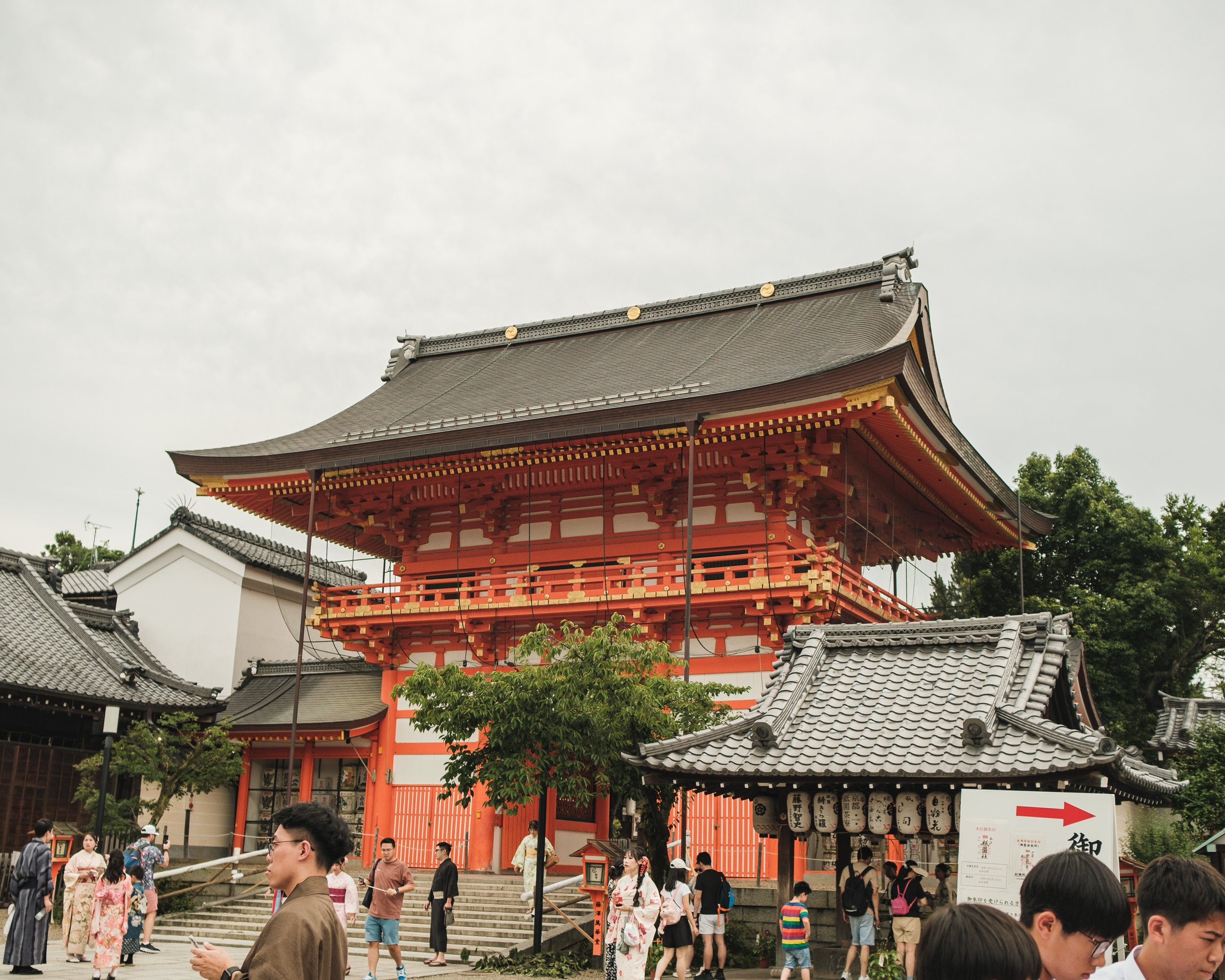 Traditional Japanese temple with a large wooden structure, pagoda-style roof, and people visiting the site.