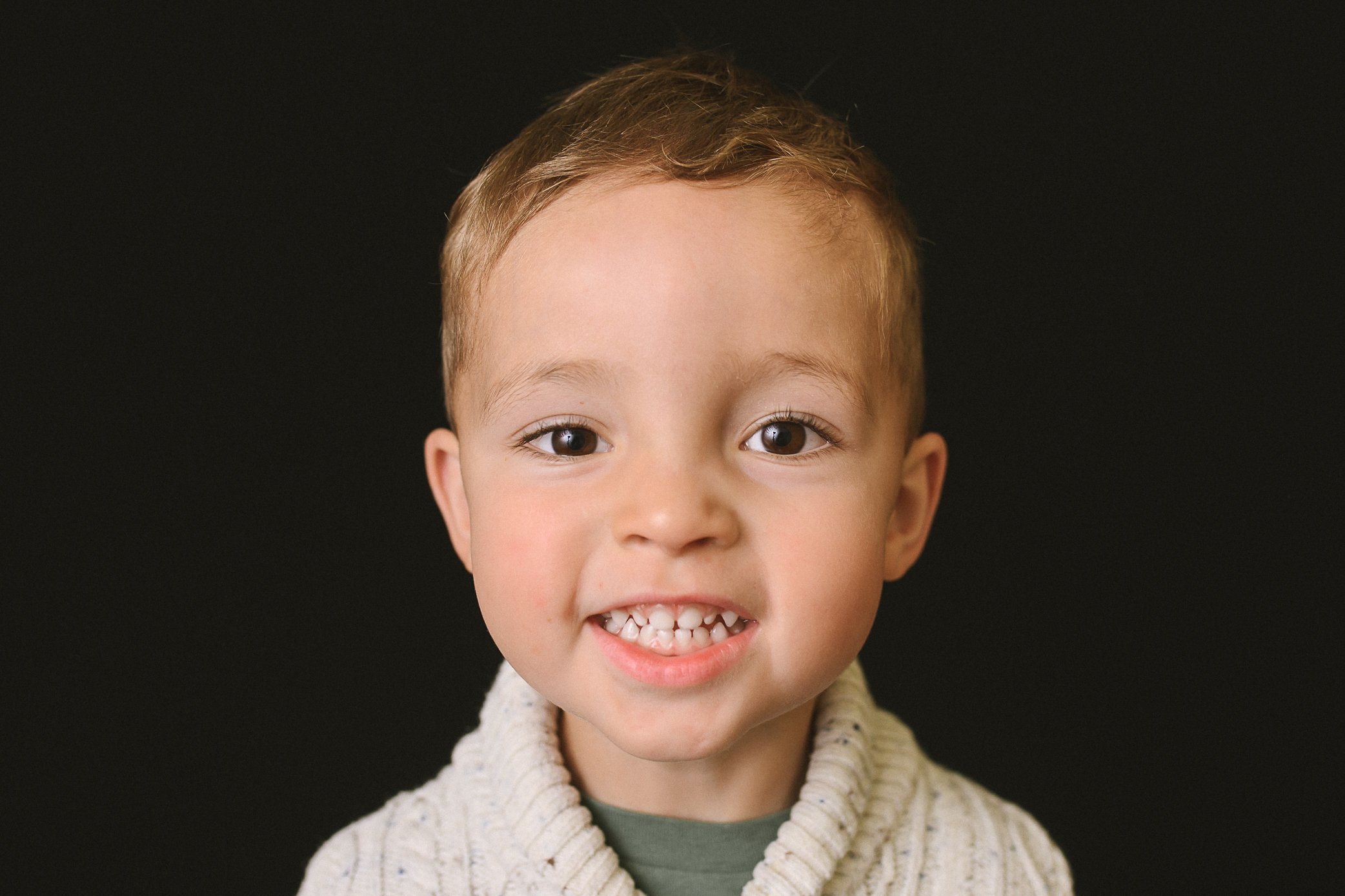 school portrait of a little boy with big brown eyes and a cheeky smile