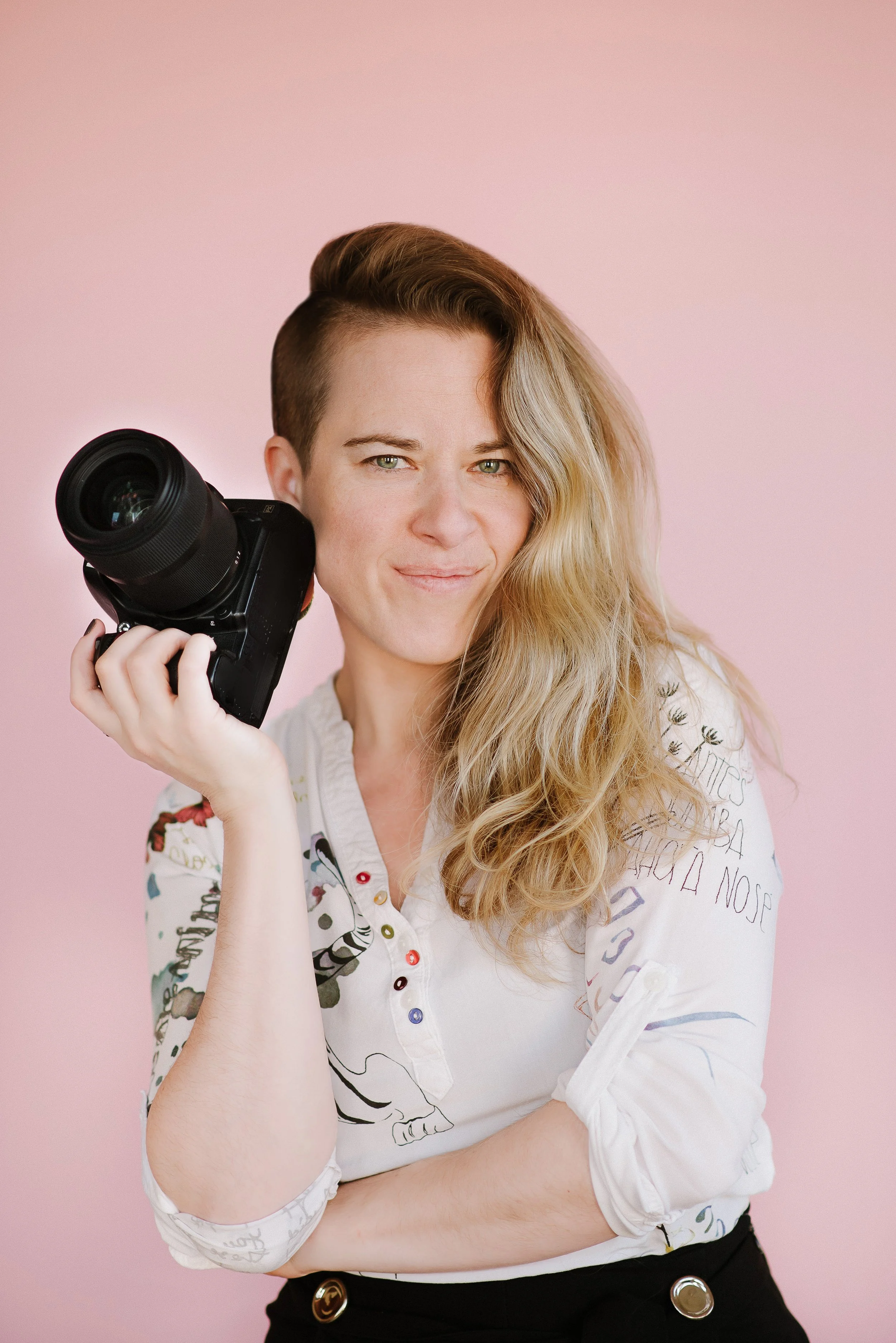 Portrait of a woman photographer with pink backdrop
