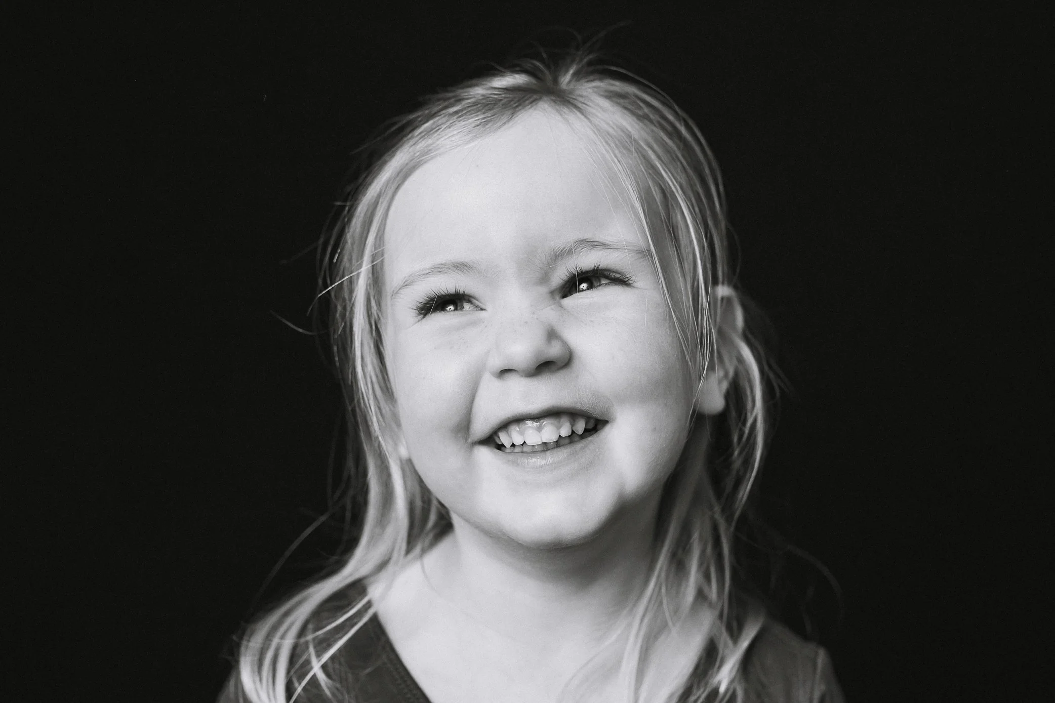 black and white portrait of a preschool girl smiling and looking up