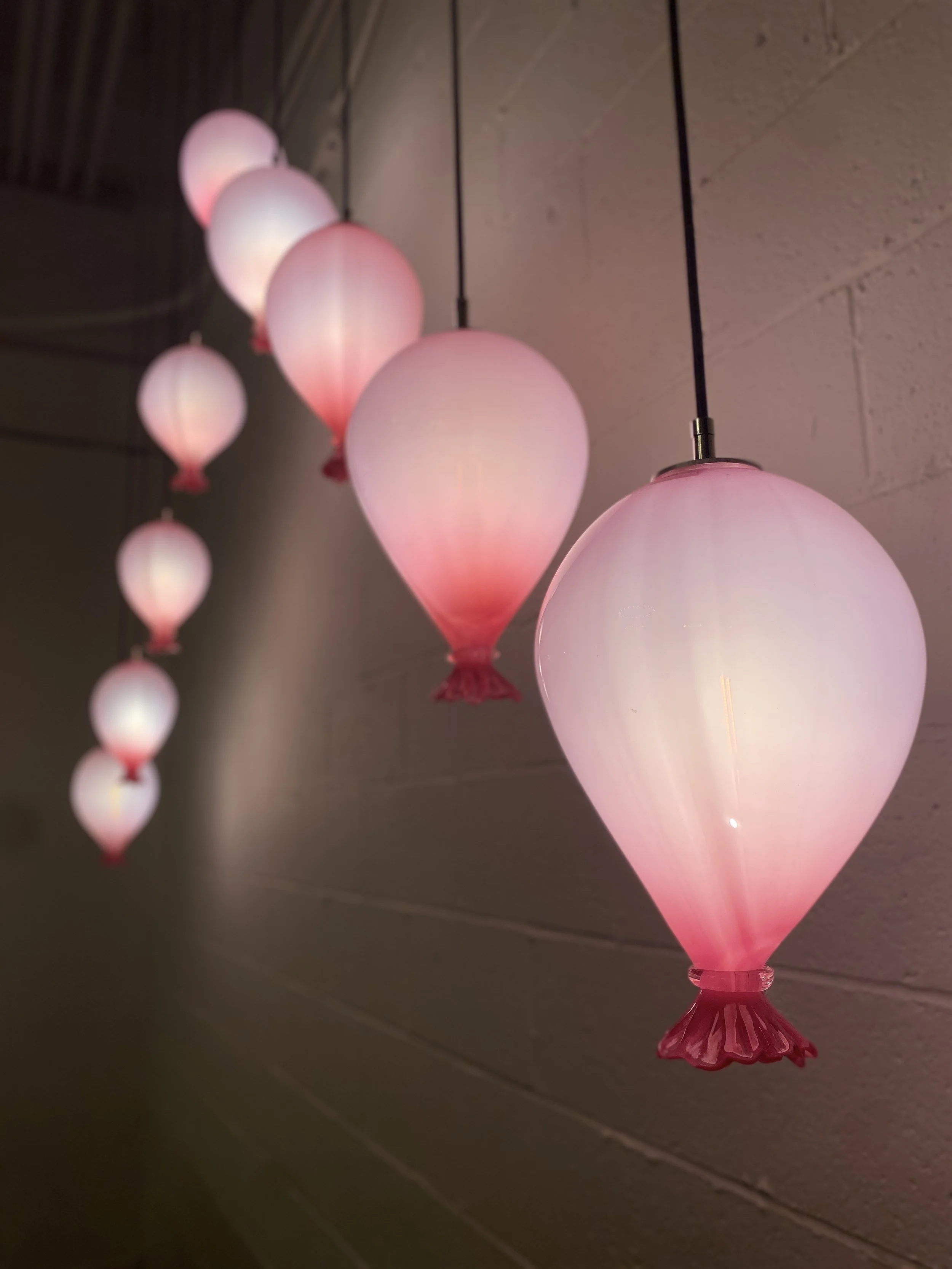 Pink and white decorative hanging glass blown balloon lights in a row