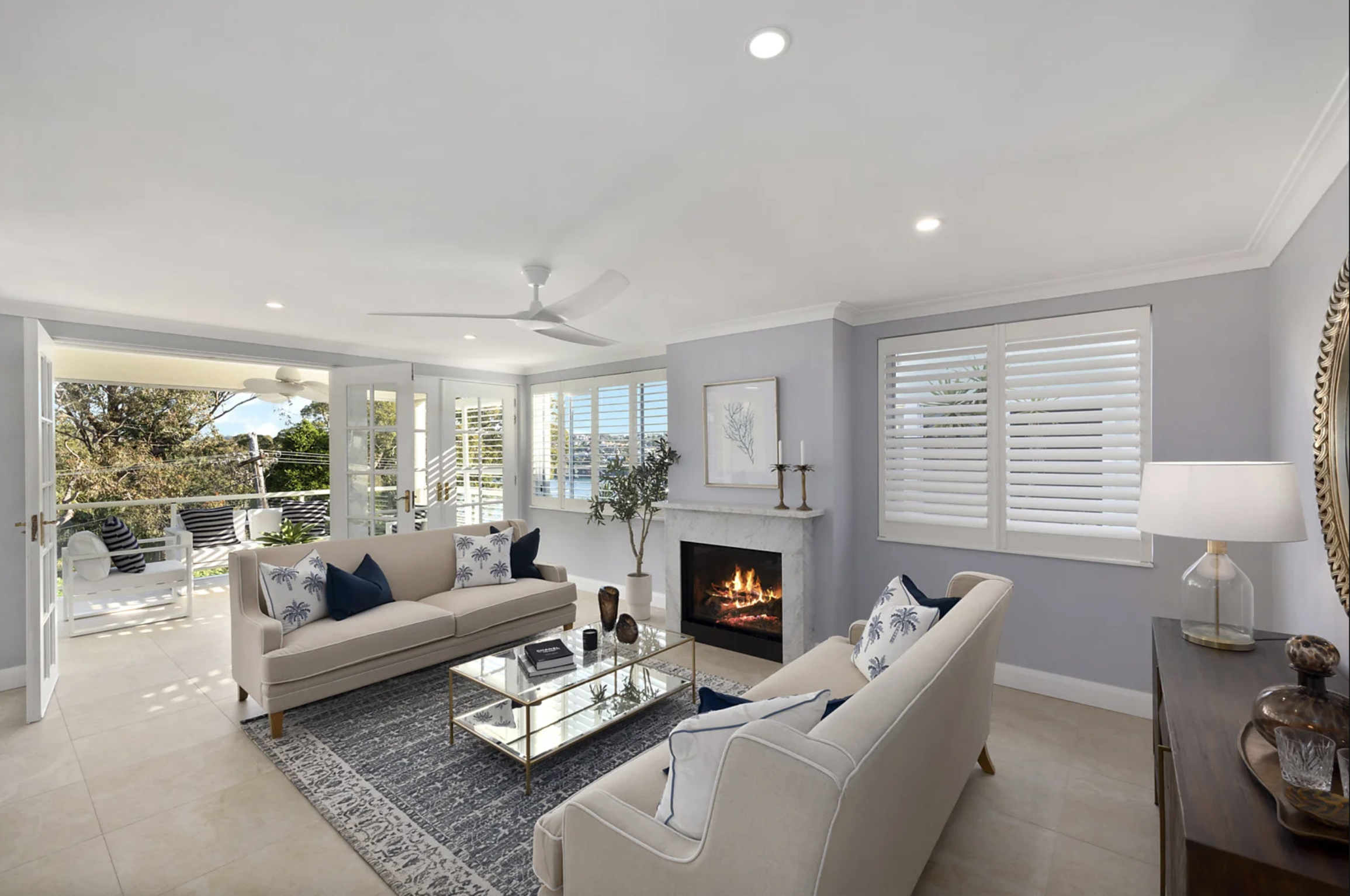 Living room styled with two sofas, blue and white rug, glass coffee table and fireplace. Clontaf