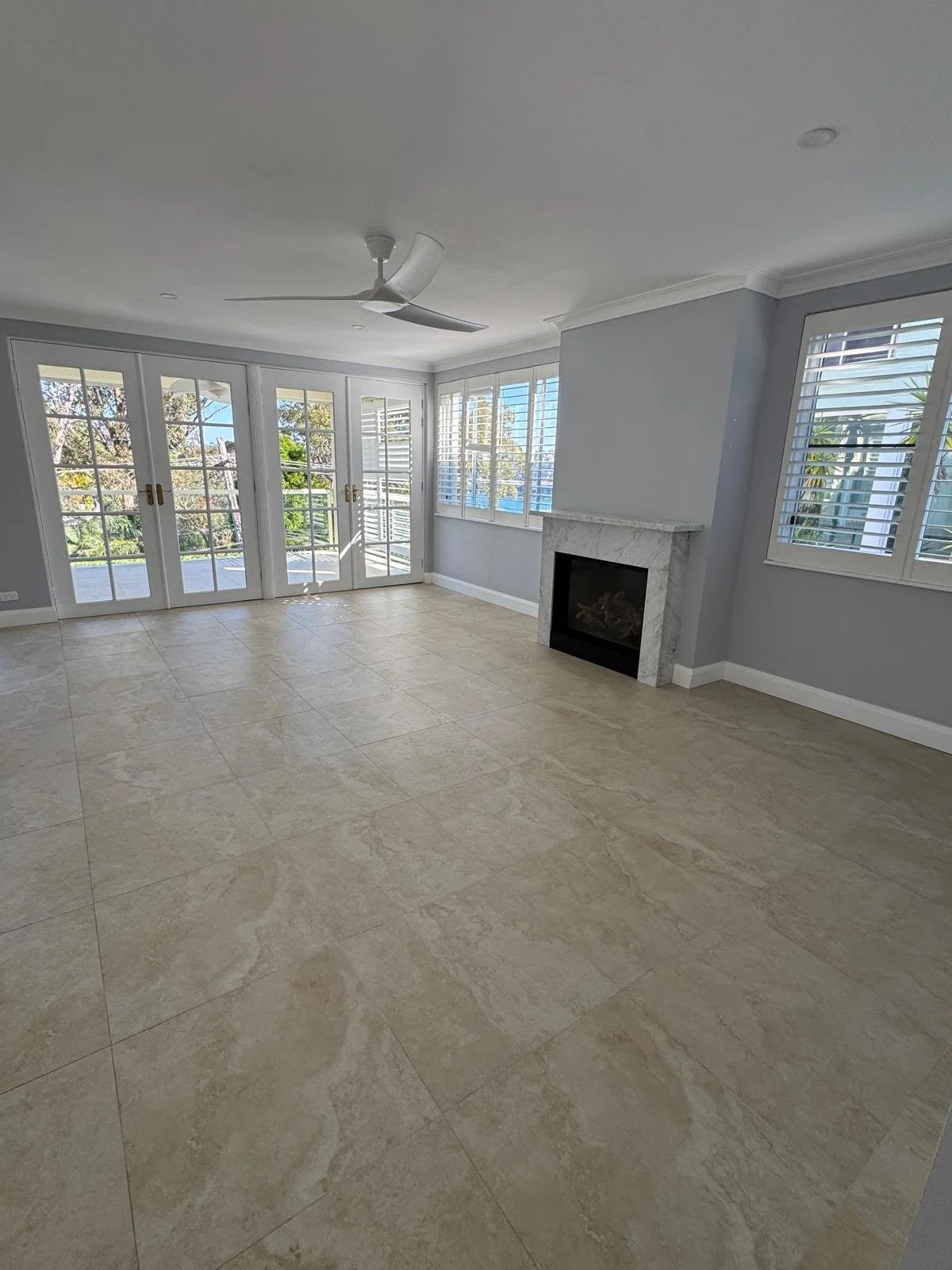 Before styling: room with a fireplace, blue walls with white doors leading to balcony. Clontaf