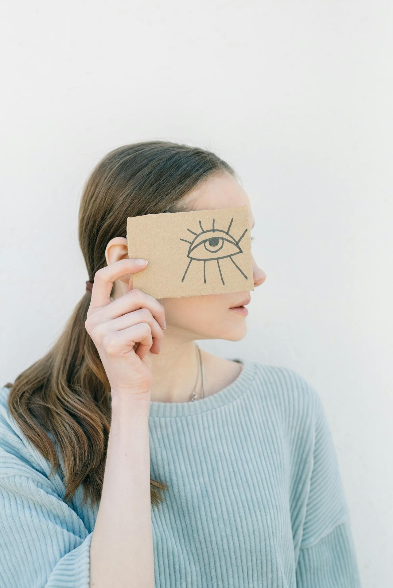 A therapist holding a card with a drawn eye over her face, symbolizing the shift from uncertainty to clarity through EMDR consultation and deeper clinical insight.
