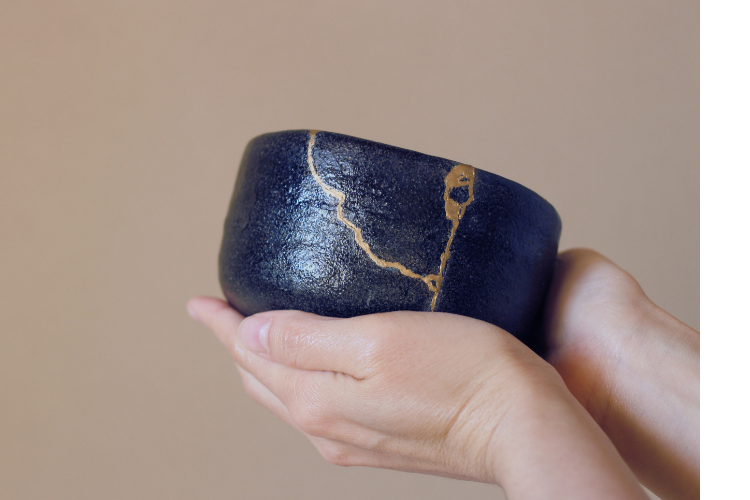 pair of hands holding a black bowl repaired in Kintsugi style; representing healing that can occur in trauma therapy.