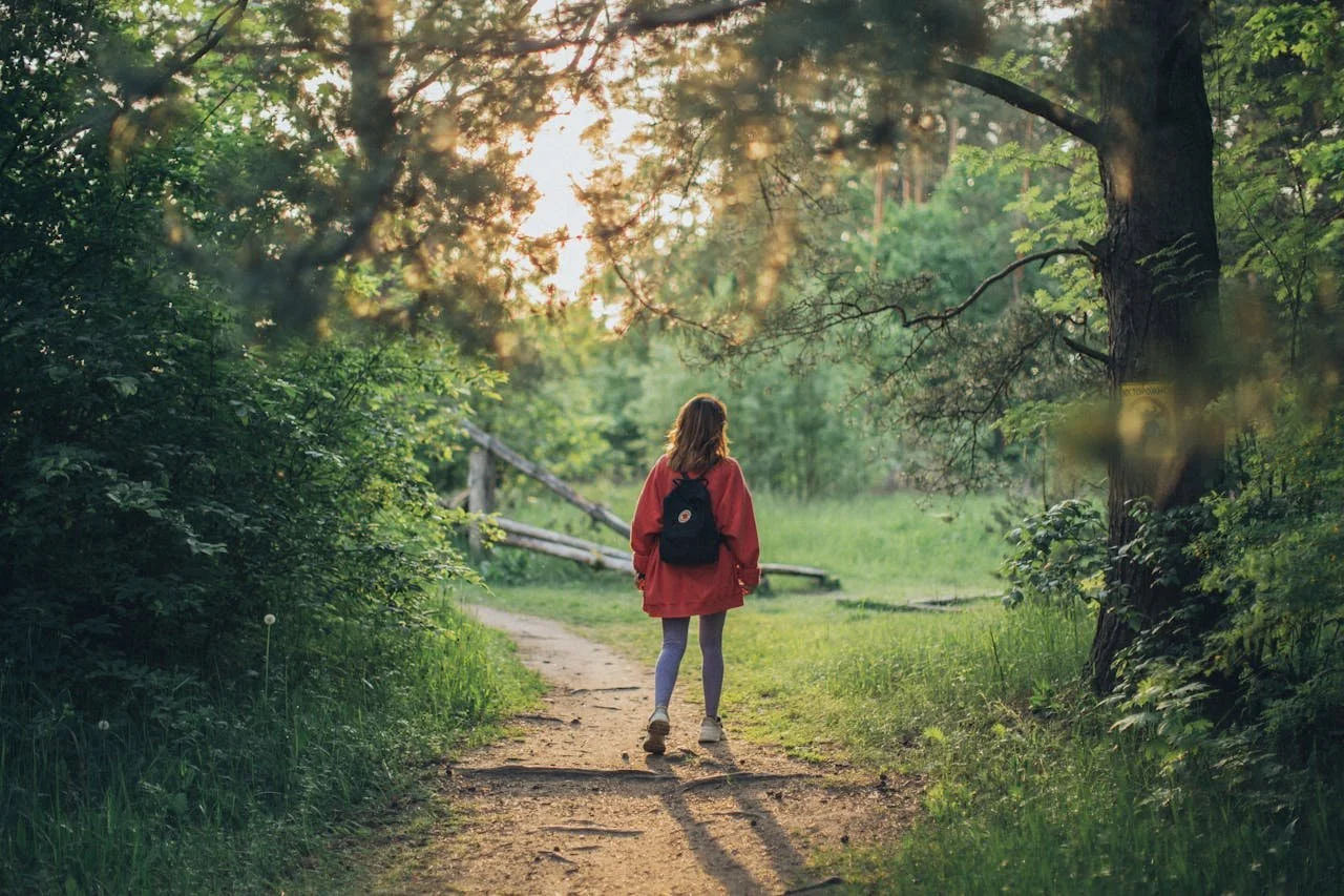 Woman walking on a forest path, symbolizing integration and continued healing after a therapy intensive