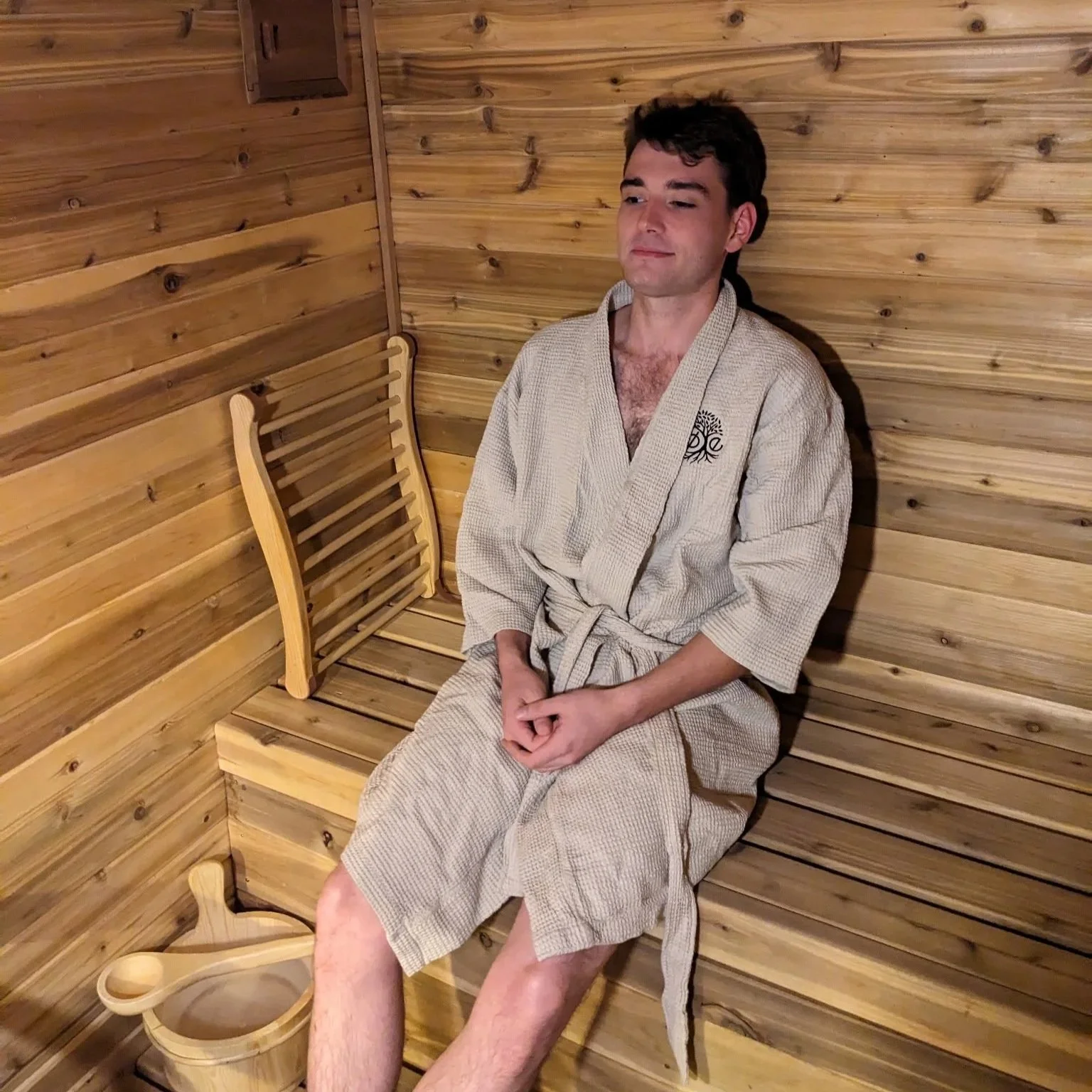 Man in robe relaxing in Finnish cedar sauna