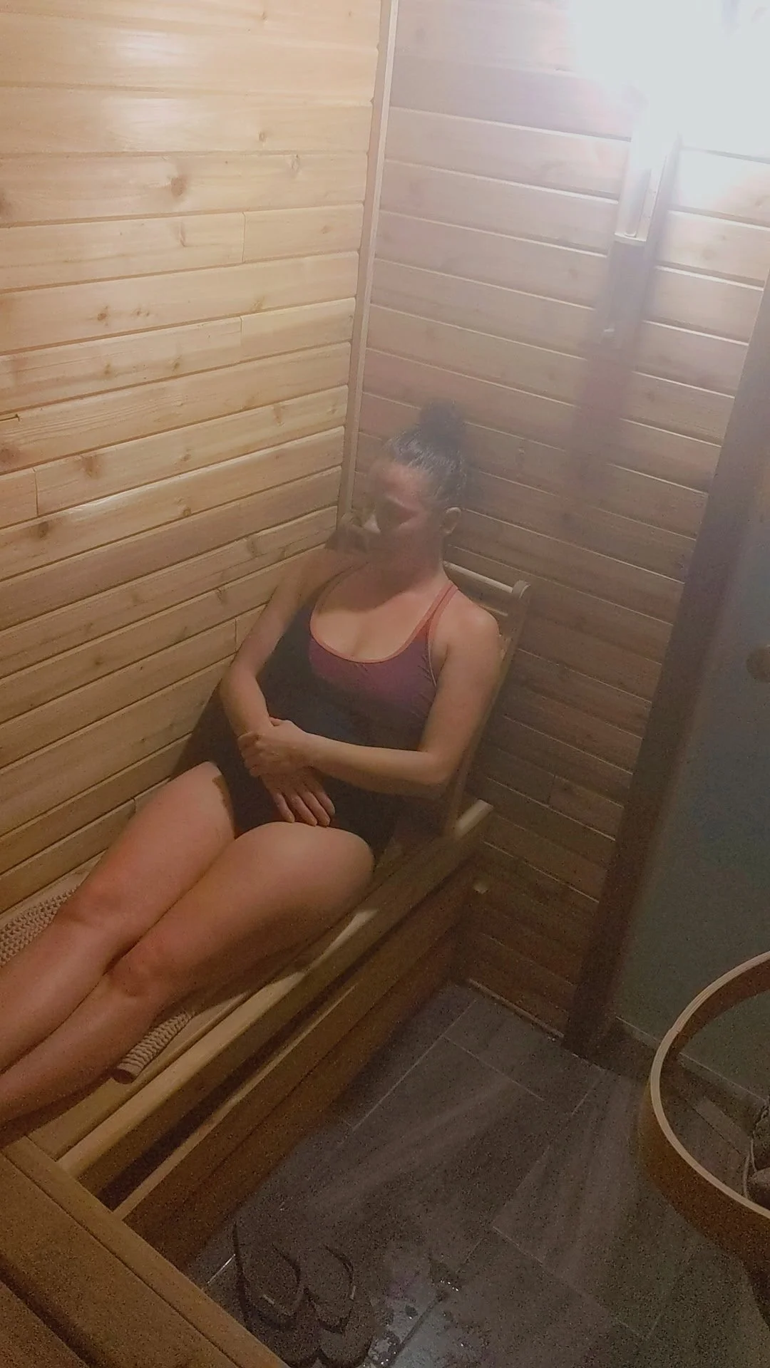 Woman reclining in steamy Finnish cedar sauna