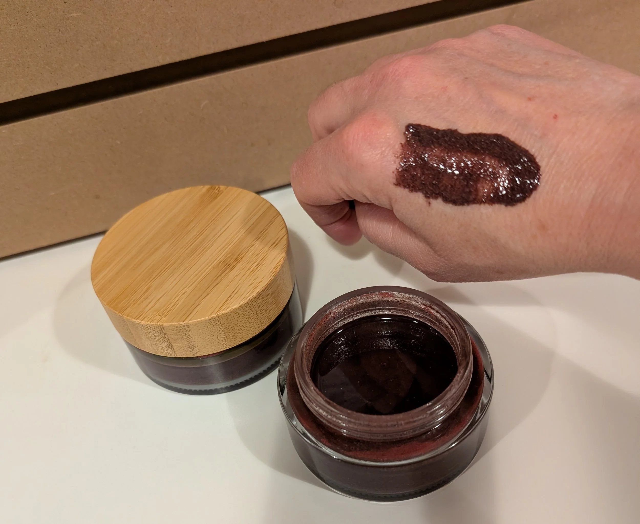 Boreal Frostbær Glow Polish on hand above open product jar.