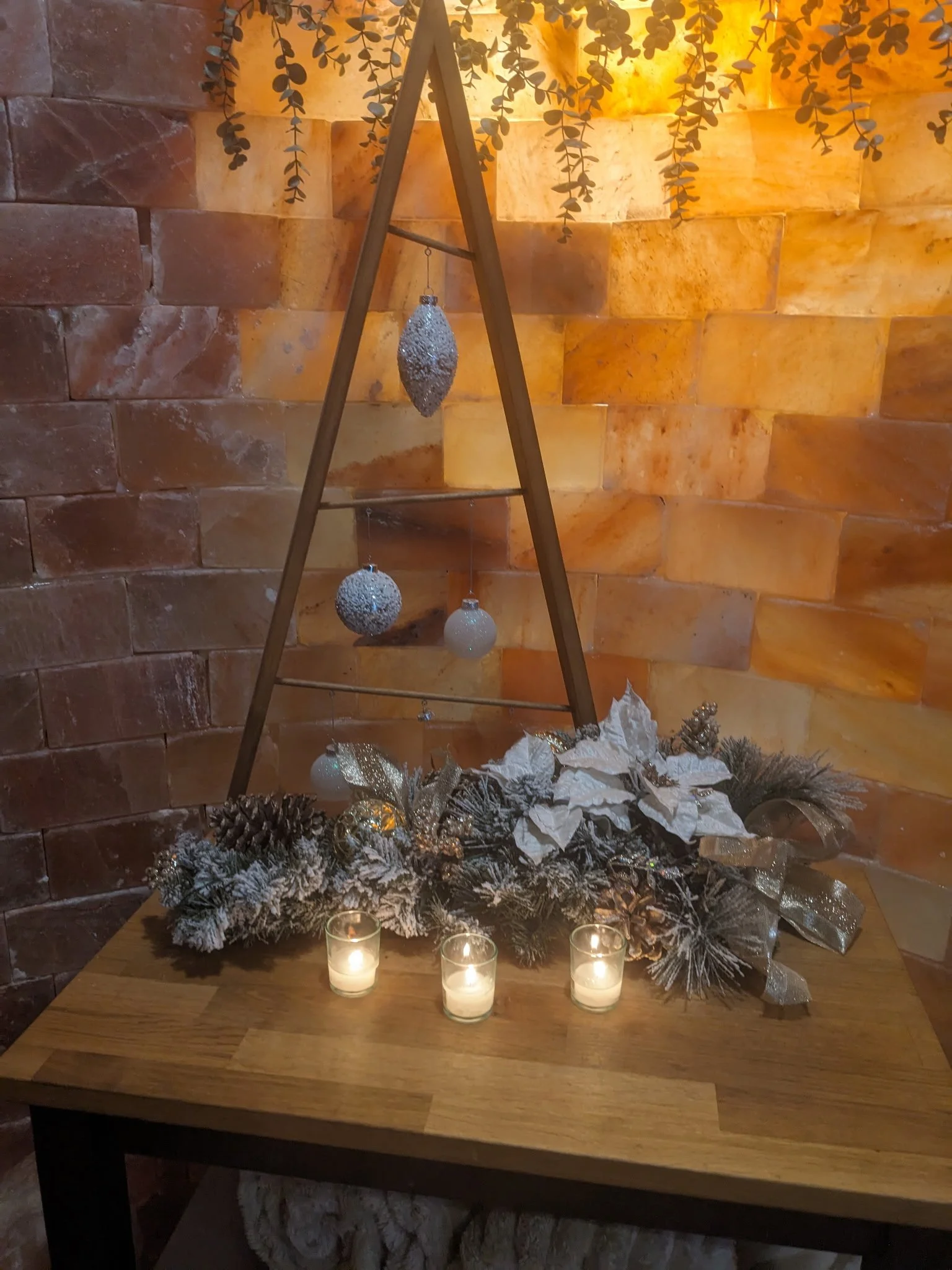 Three bright voltive candles and Christmas decorations in front of Søle's salt wall.