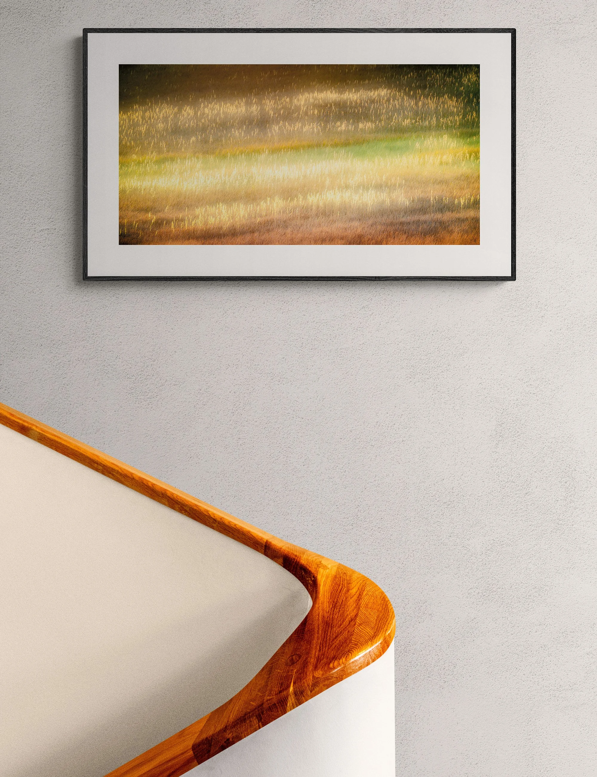 “Prairie Dawn” abstract landscape print by Ian J. Muirhead Arts above a curved timber staircase in a minimalist interior. Soft golden grasses and painterly light create a warm atmospheric scene.