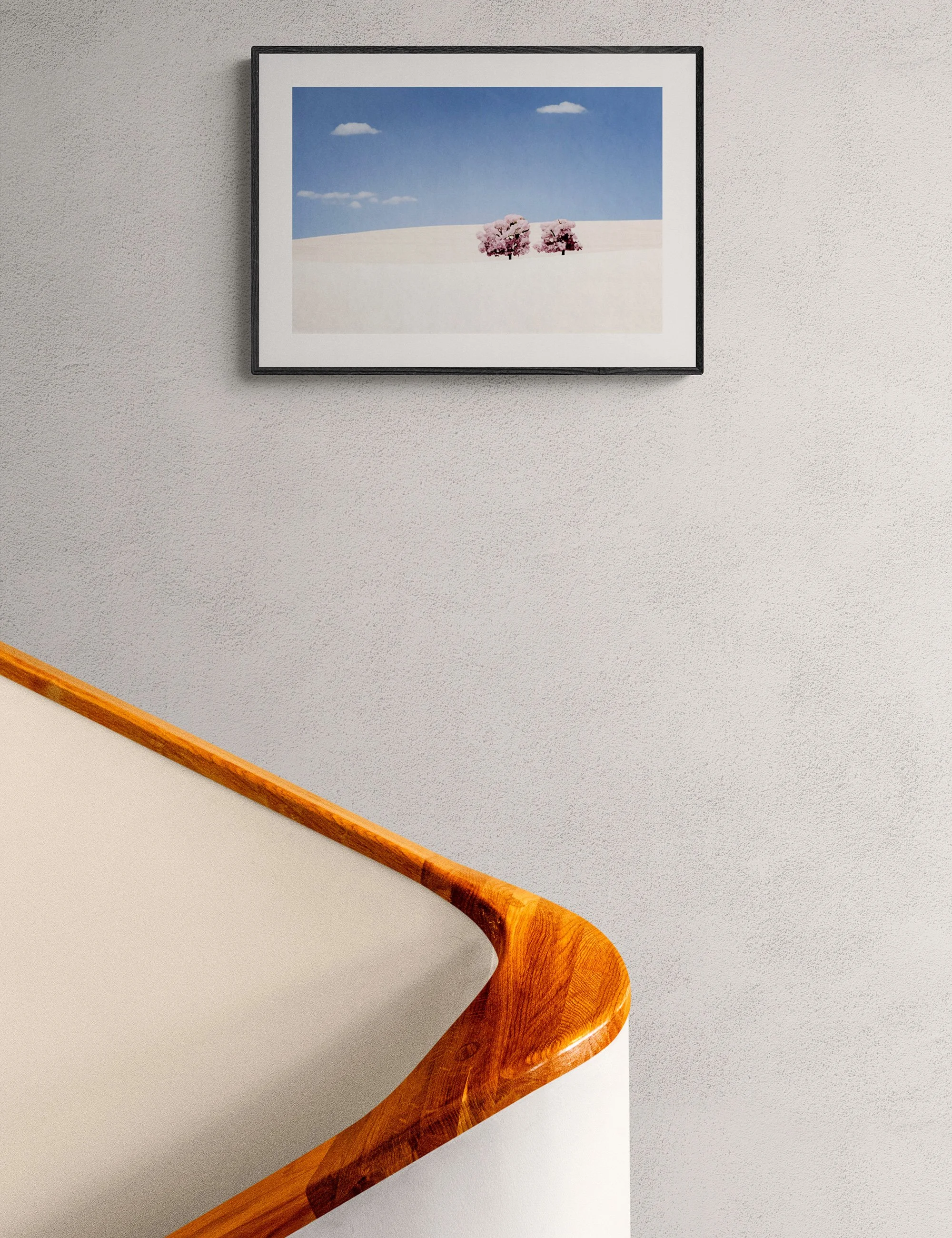 “Surreal Fields of Wheat” framed fine art print by Ian J. Muirhead Arts above a curved timber staircase in a minimalist interior.