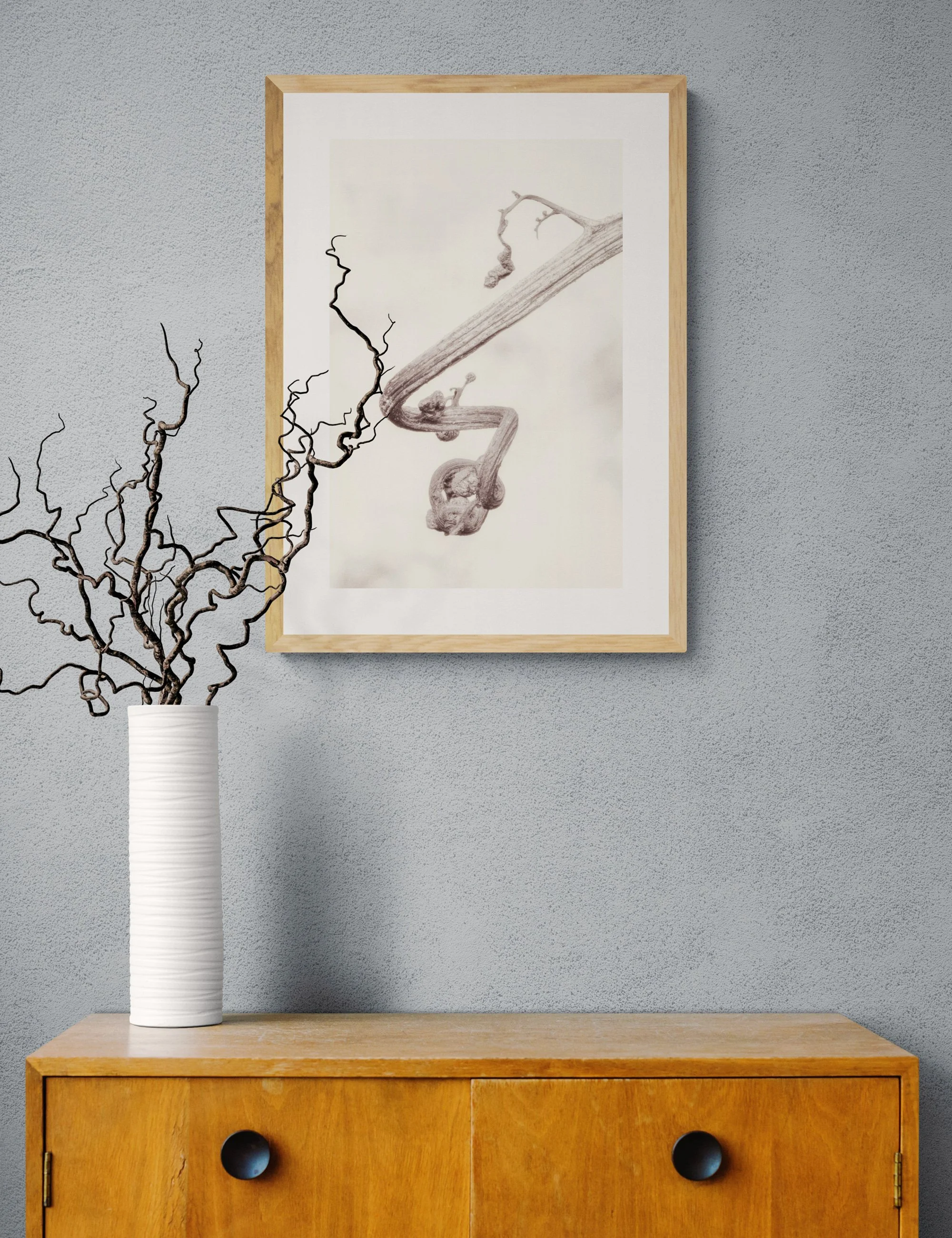 “Grace in the Unfinished” from the Fronded Forms fern series by Ian J. Muirhead Arts, displayed in a minimalist interior with a light timber frame and sculptural branches.