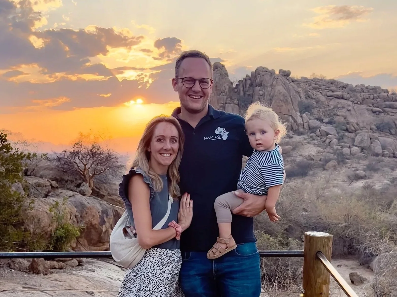 Familie mit Mann, Frau und kleinem Mädchen vor einer Felslandschaft bei Sonnenuntergang