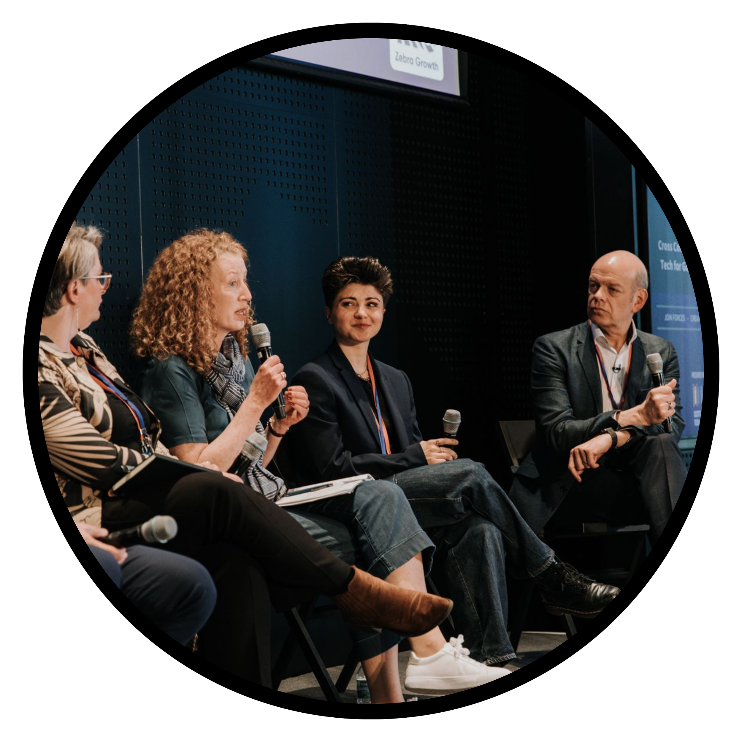 Image in a circular black frame of people talking on stage
