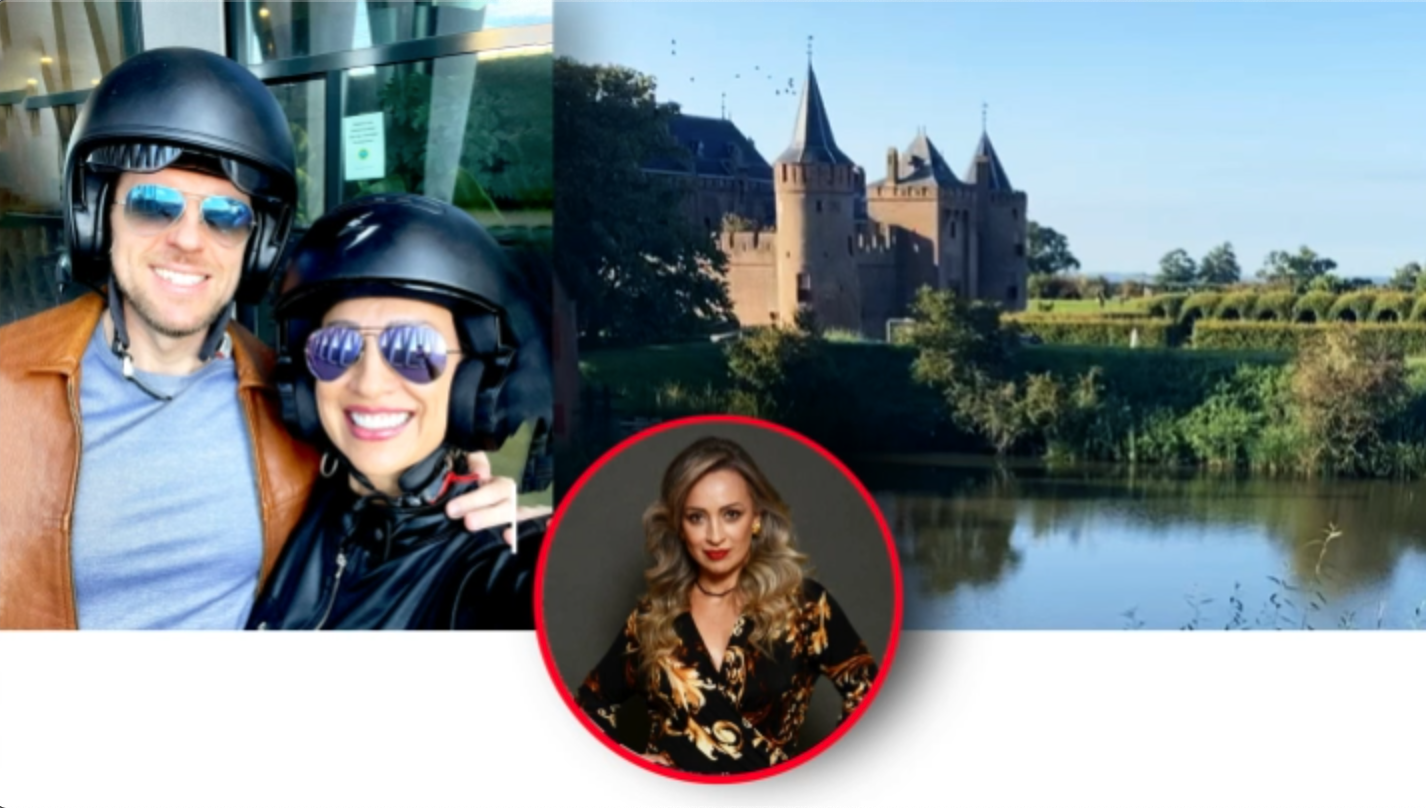 A couple wearing helmets and sunglasses taking a selfie outdoors. There is a castle and a river in the background. A woman with blonde curly hair in a black floral top is shown in a circular inset.