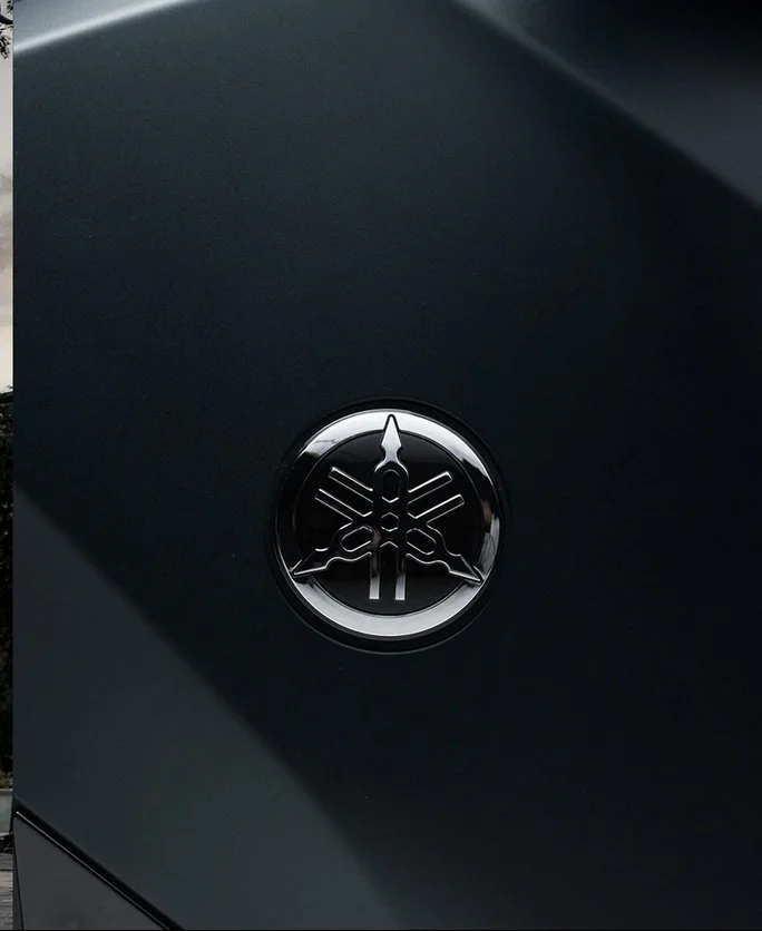 Close-up of a Yamaha logo emblem on a dark-colored surface.