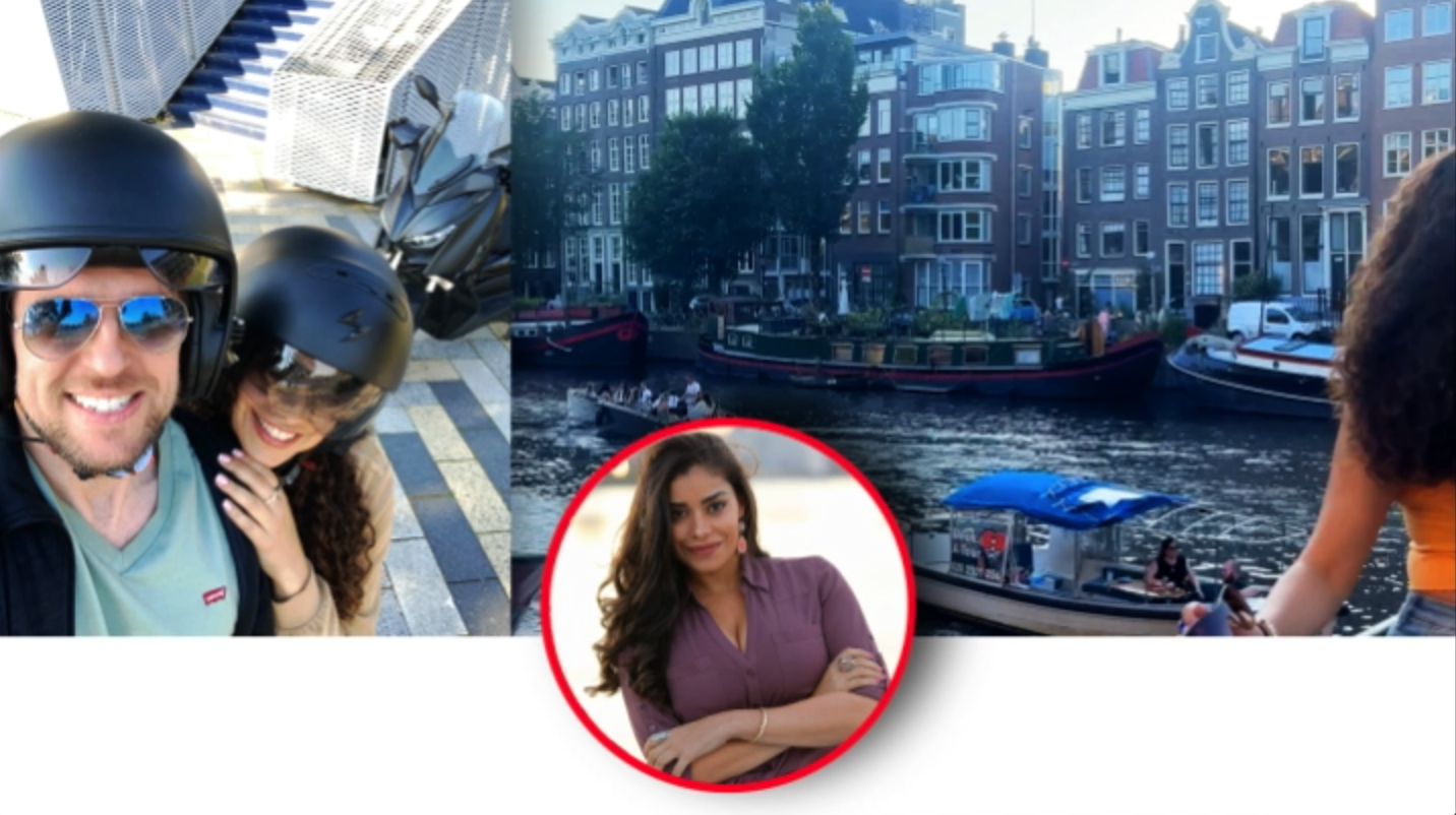 People taking a selfie on a bike with a city canal in the background, featuring boats and traditional European buildings.