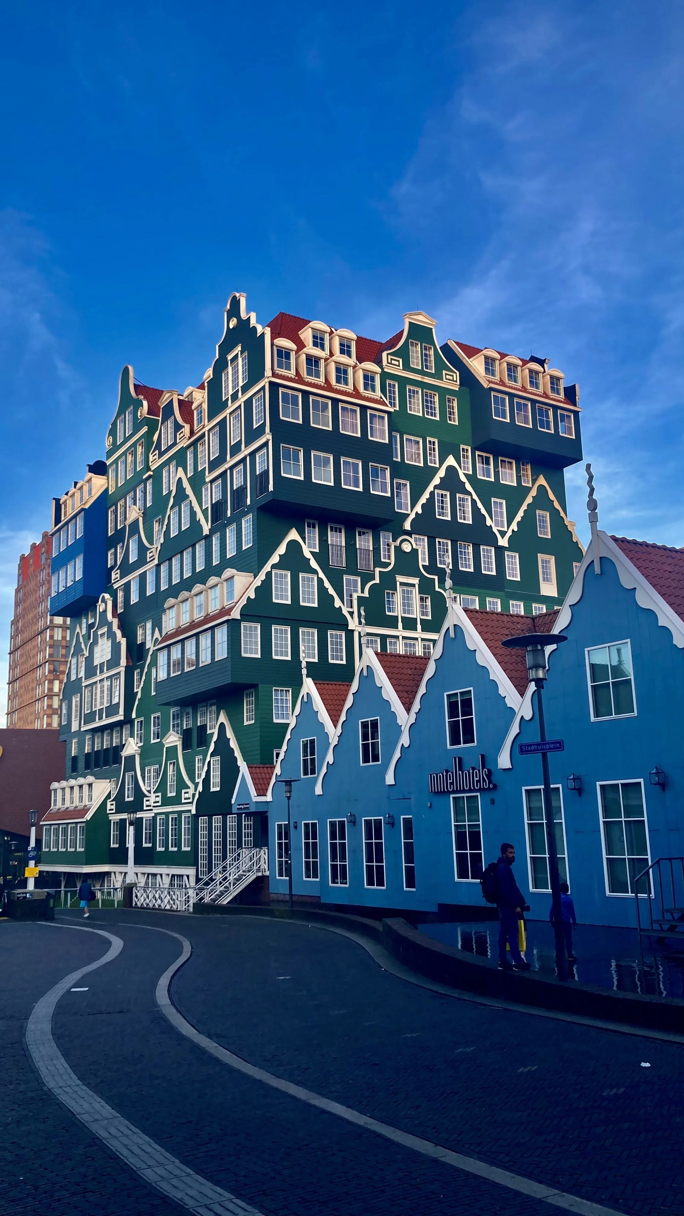 Colorful, stacked, traditional Dutch-style houses with stepped gables and red roofs on a bright, clear day.