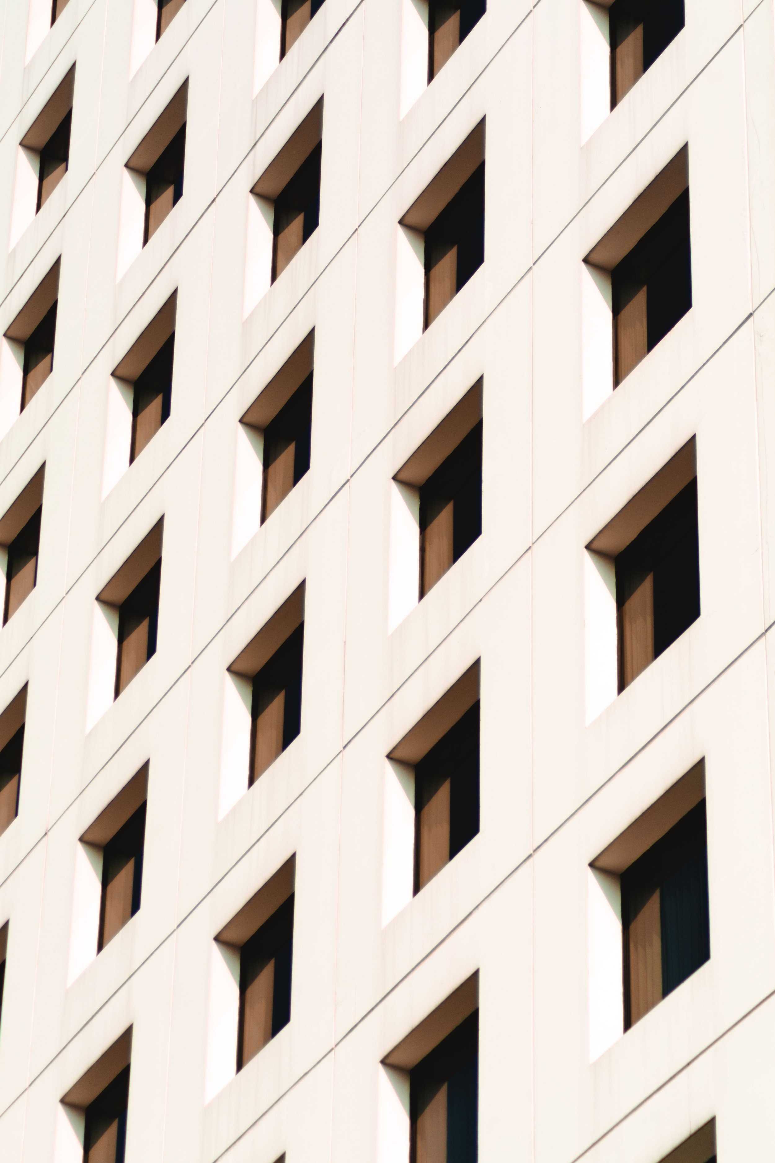 Close-up view of a modern building's exterior with a repeating pattern of rectangular windows and white facade panels creating a geometric design.