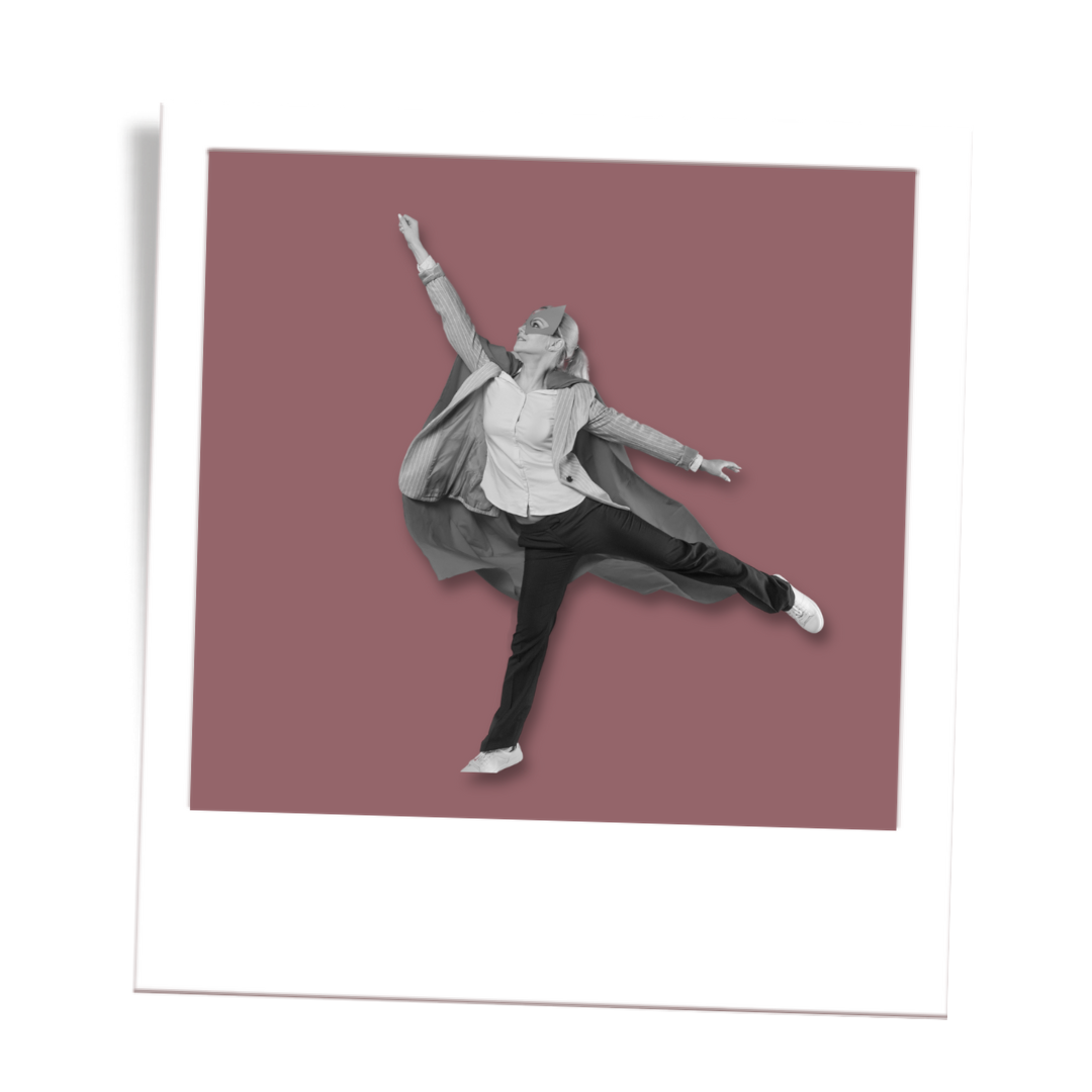 Woman in business attire and a superhero cape jumping with one arm raised, on a pink background, in a photo with a Polaroid frame. Confident millennial woman after completing confidence course