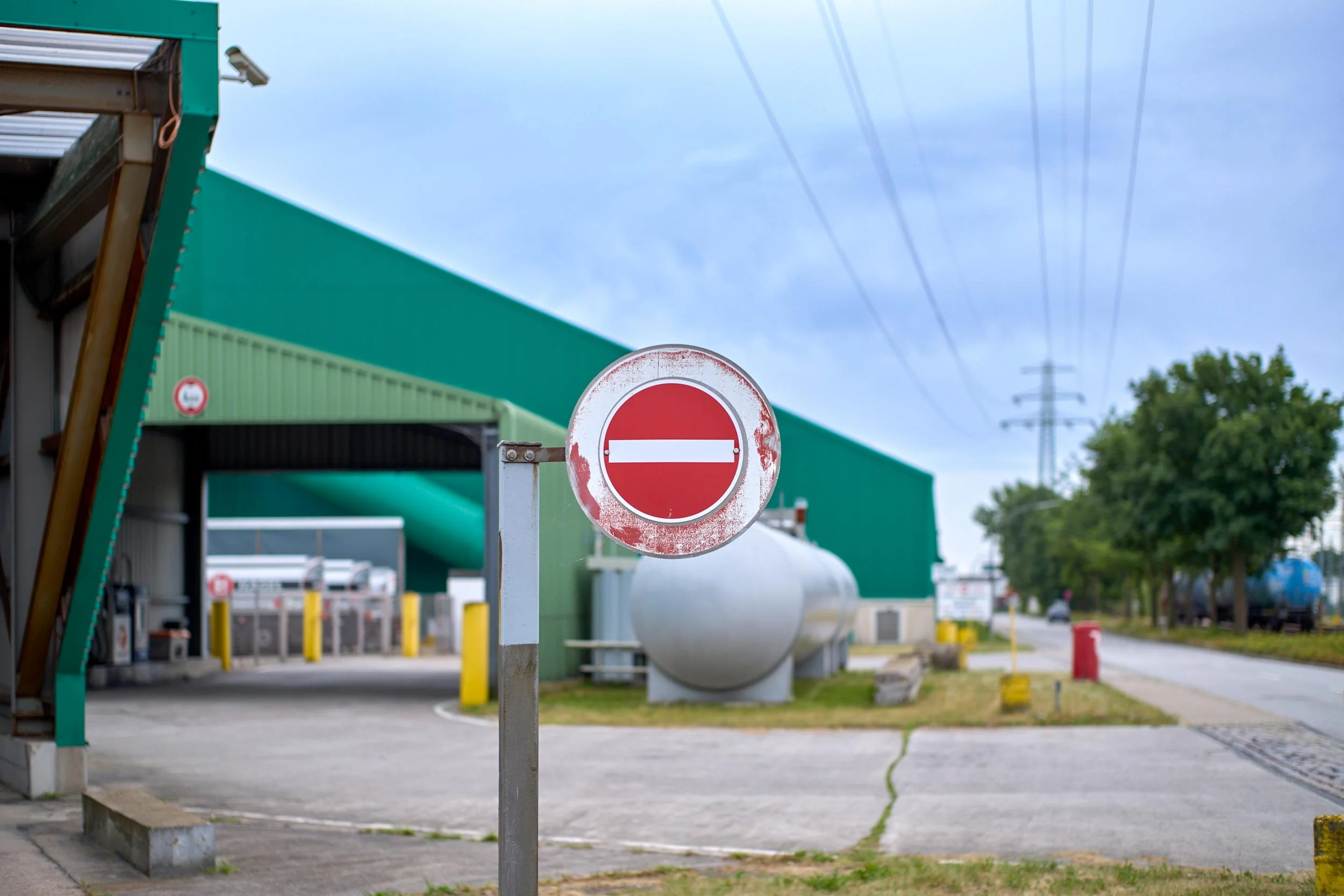 Rundes Verkehrsschild mit waagerechtem weißen Balken an einer Zufahrt zu einem Industriegelände.