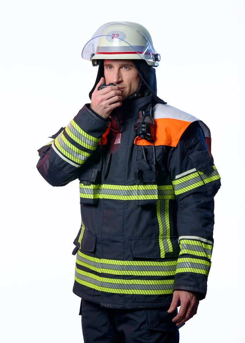 Feuerwehrmann in Einsatzkleidung mit Funkgerät vor hellem Hintergrund