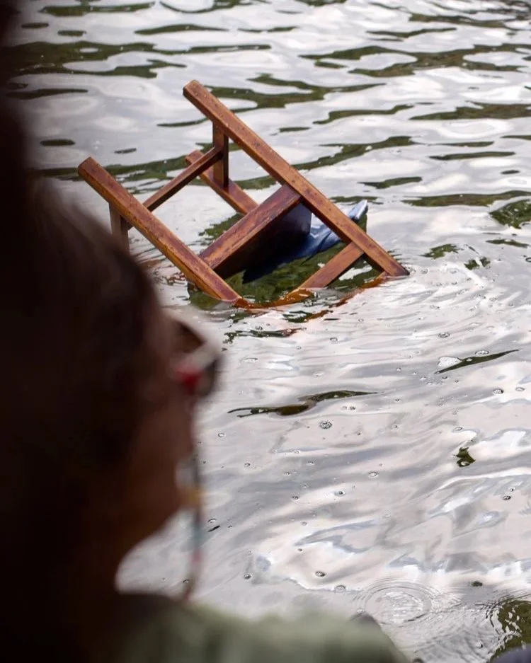 Das Bild zeigt einen hölzernen Stuhl, der teilweise im Wasser versunken ist.