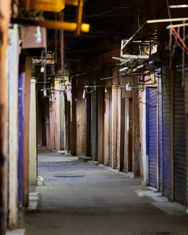 Leerer Basar in der Dämmerung: Ein stiller, menschenleerer Basar mit verschlossenen Läden und verworrenen Kabeln an der Decke. Die warme Beleuchtung der wenigen Lichtquellen und die engen Gassen schaffen eine mystische Atmosphäre.