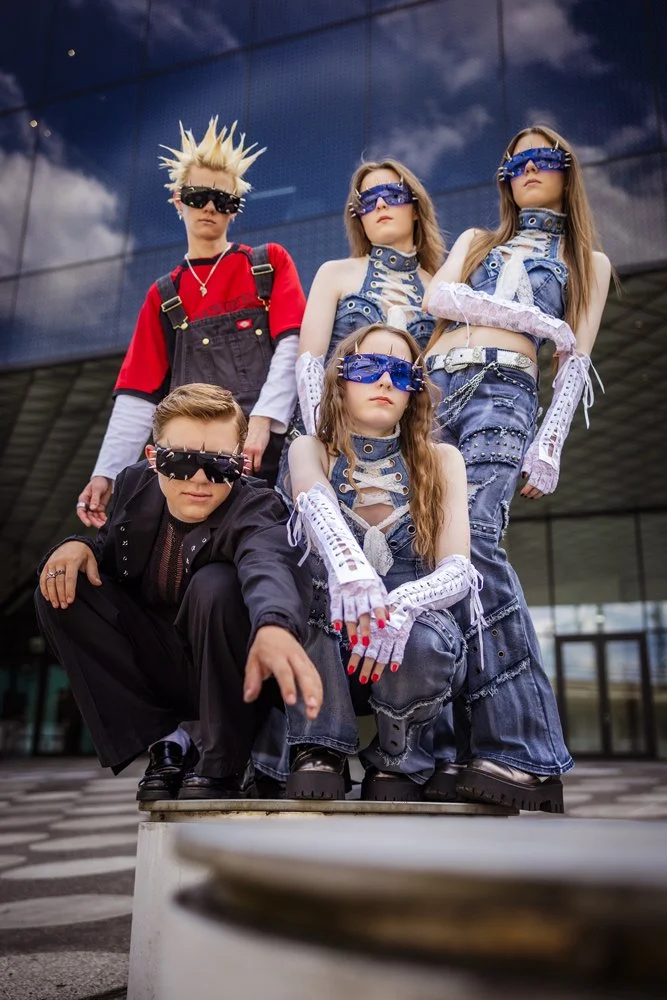 Fünf Mitglieder der Band III RIØT posieren vor der geometrischen Fassade des Futuriums in Berlin.