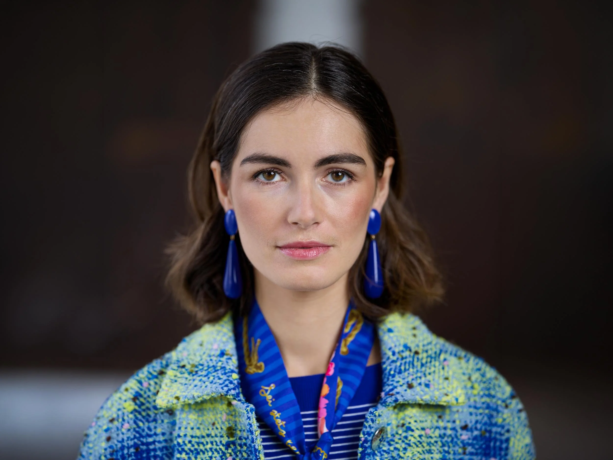 Portrait einer Frau mit blauen Ohrringen, blauem Schal und heller Tweedjacke