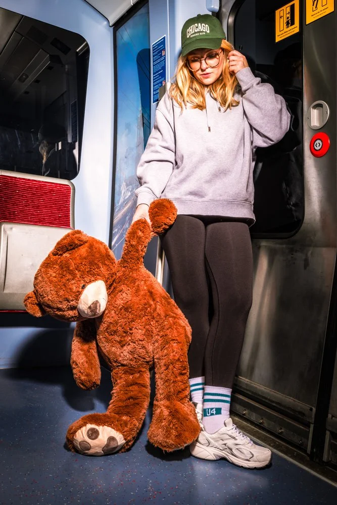Model mit Teddy im U-Bahn-Wagen trägt Hochbahn-Socken und weiße Sneaker.