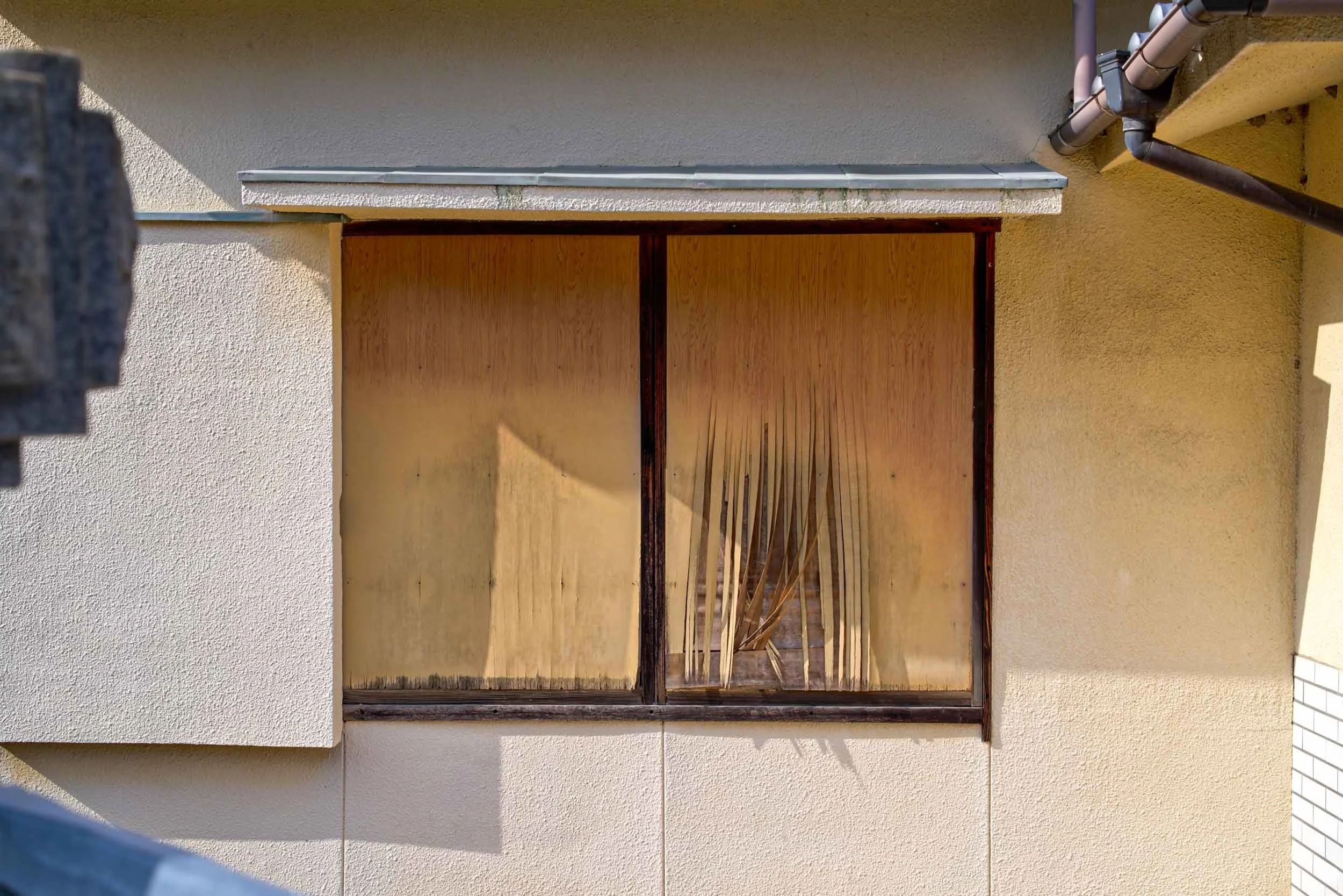 Altes Fenster mit geschlossenen Jalousien an einer Hauswand auf Teshima, Japan.