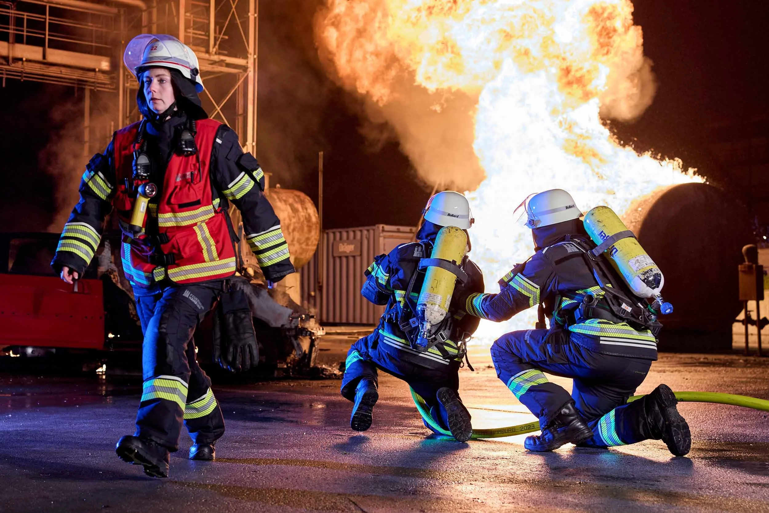 Feuerwehrkräfte bei einem Löscheinsatz vor einer großen Explosion und Flammenentwicklung